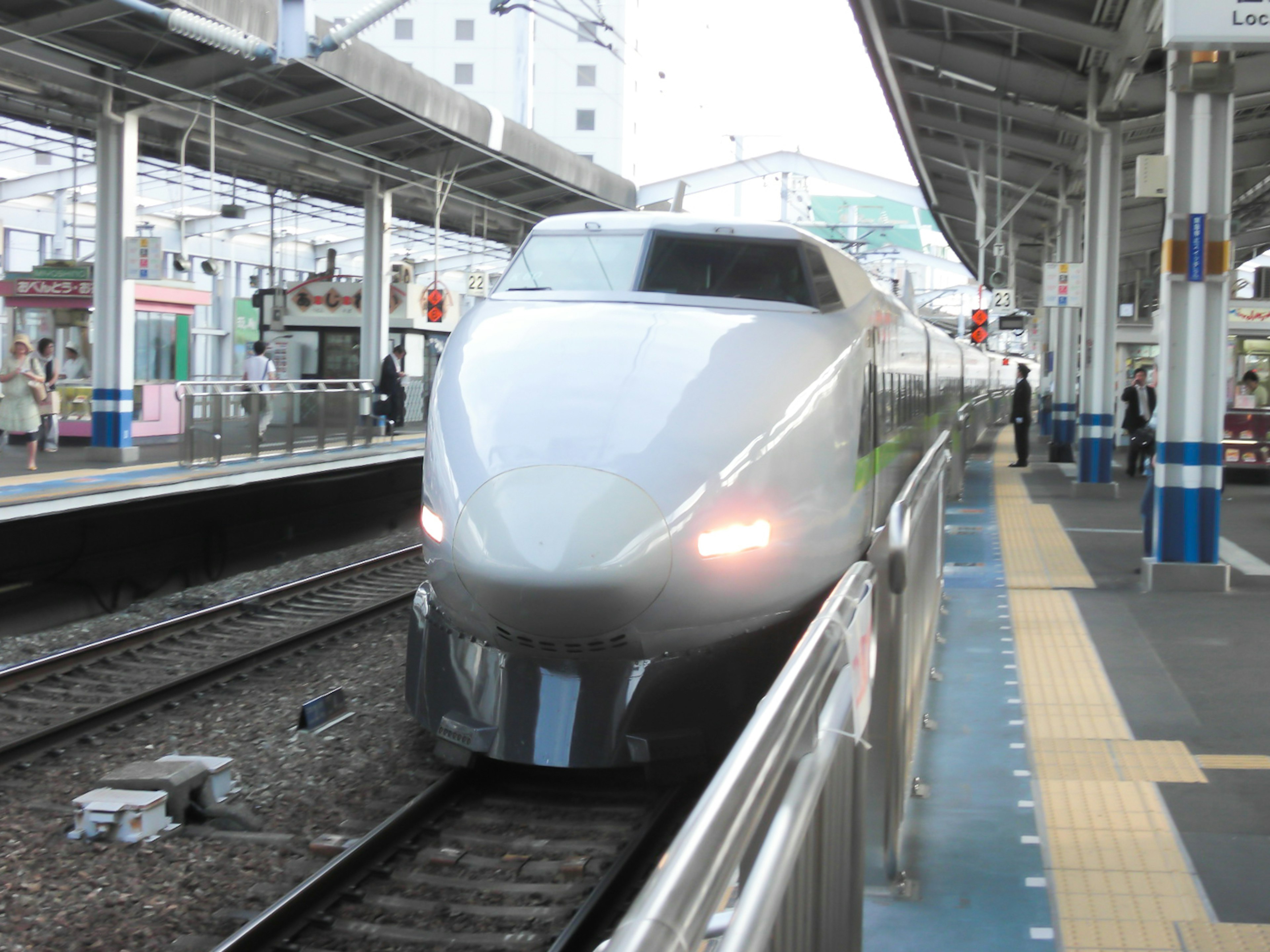 Shinkansen tiba di stasiun dengan rel dan platform terlihat