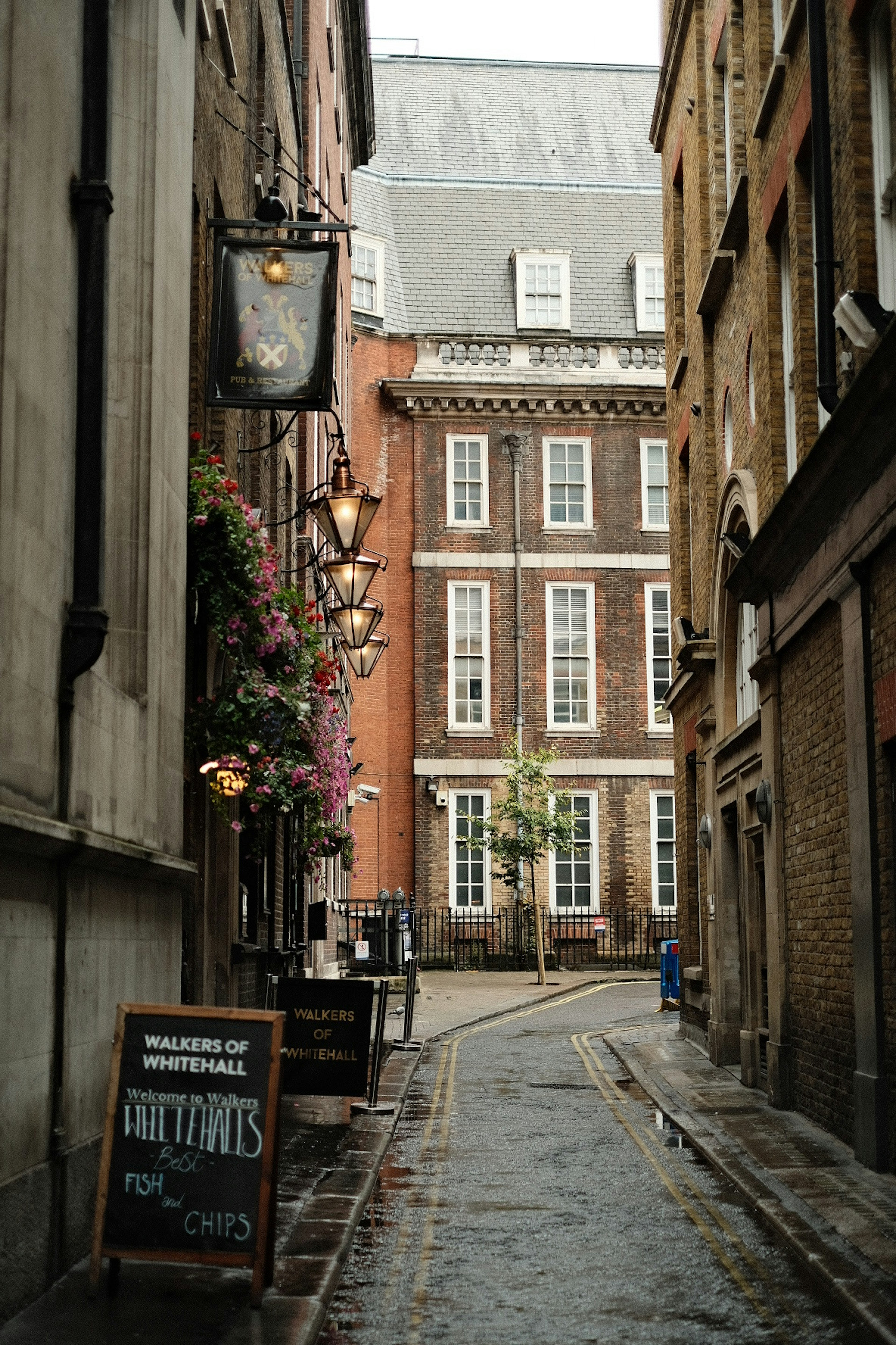 Narrow alley in London on a rainy day featuring a cafe and historic buildings