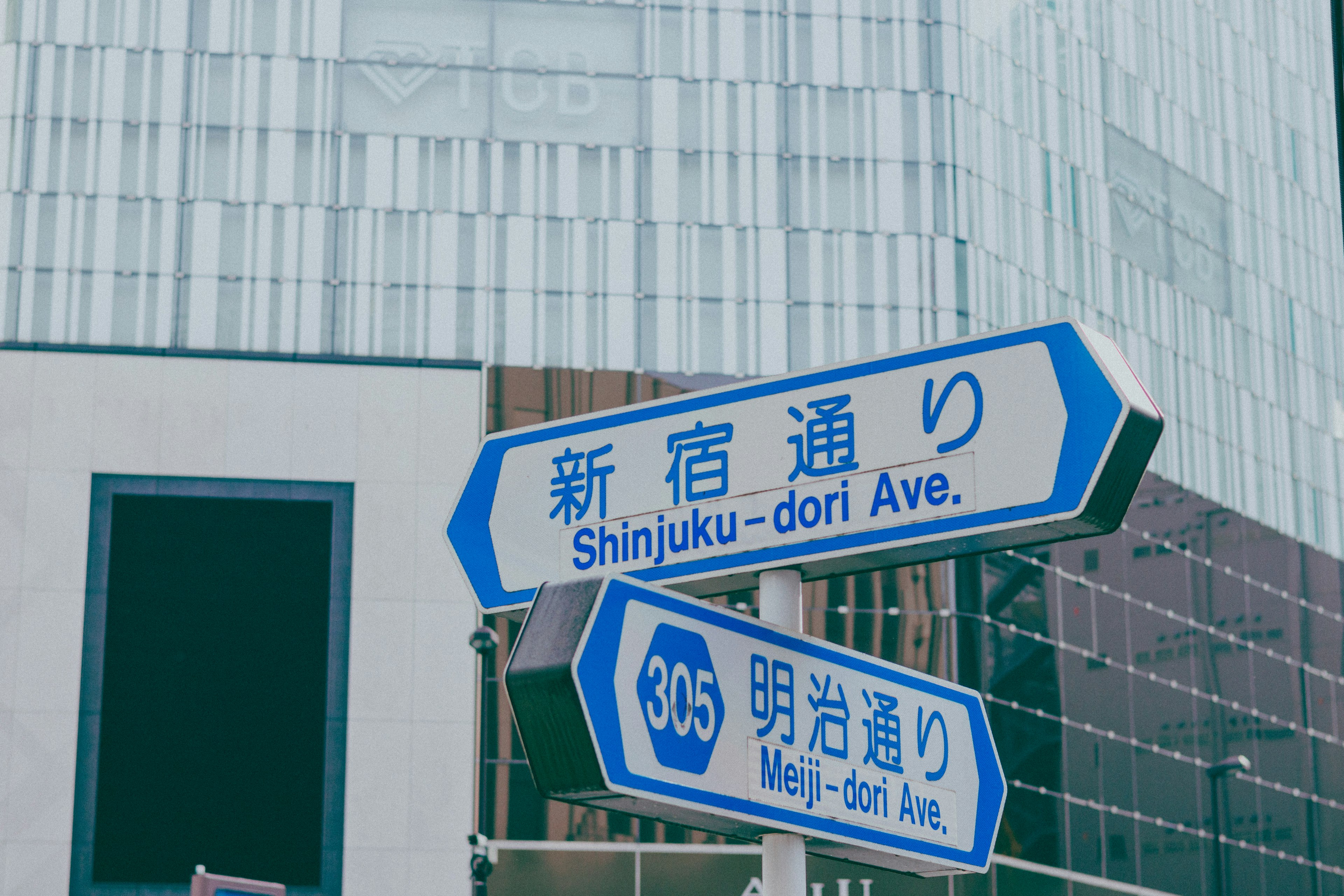 Blue street signs for Shinjuku-dori Ave and Meiji-dori with modern buildings