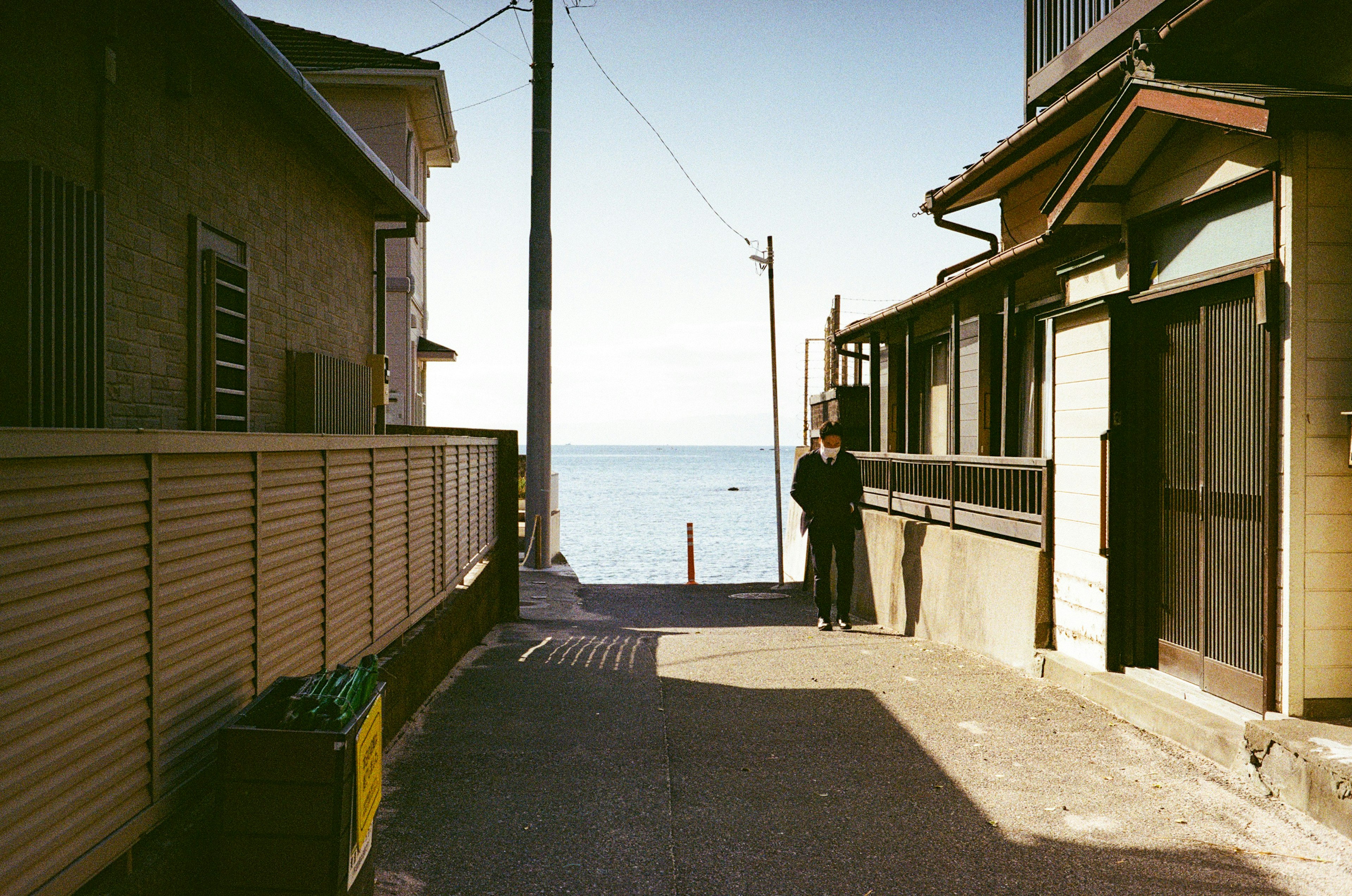 Person standing on a street near the ocean with houses