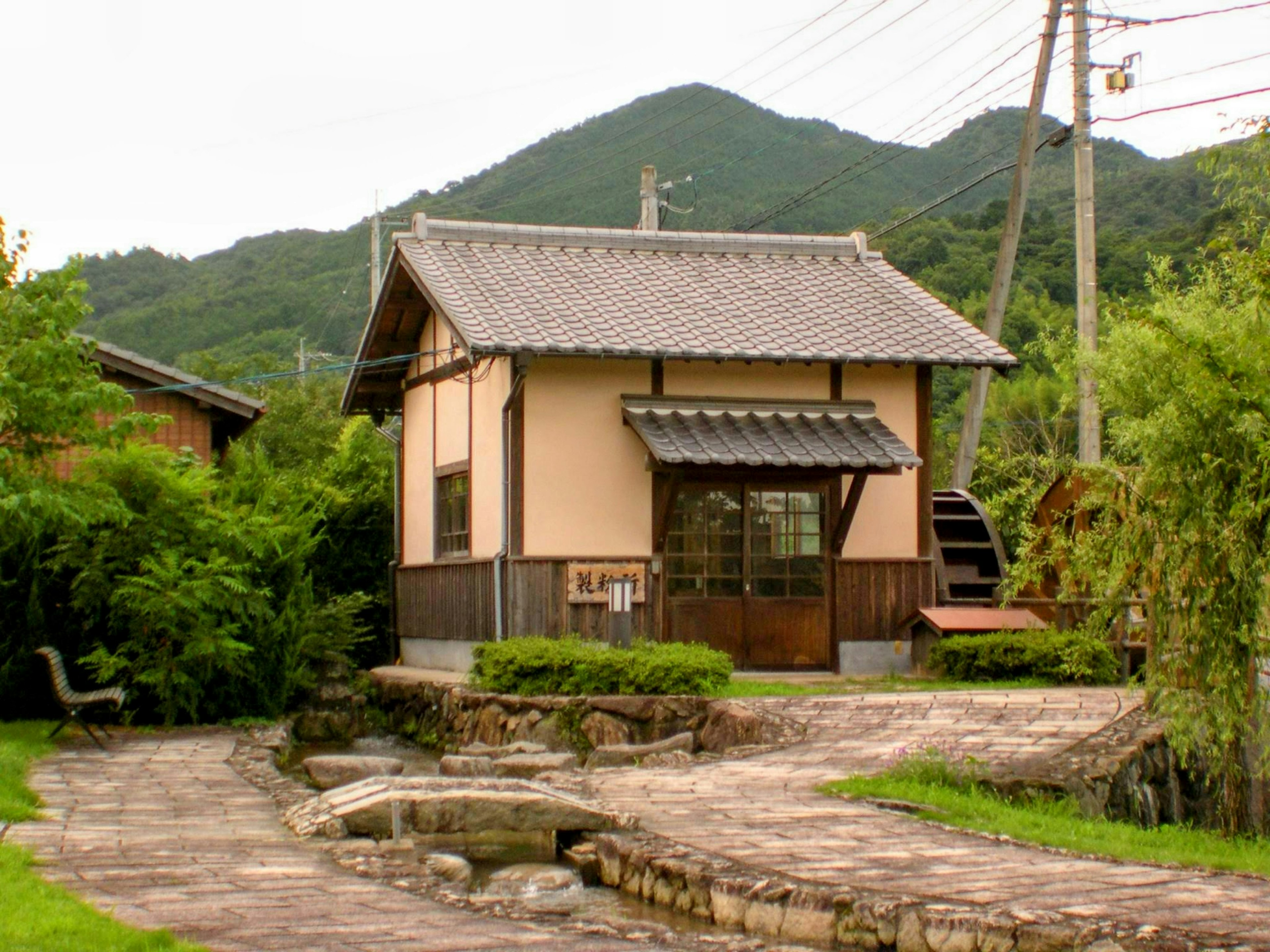 Maison japonaise traditionnelle entourée de verdure luxuriante et de montagnes