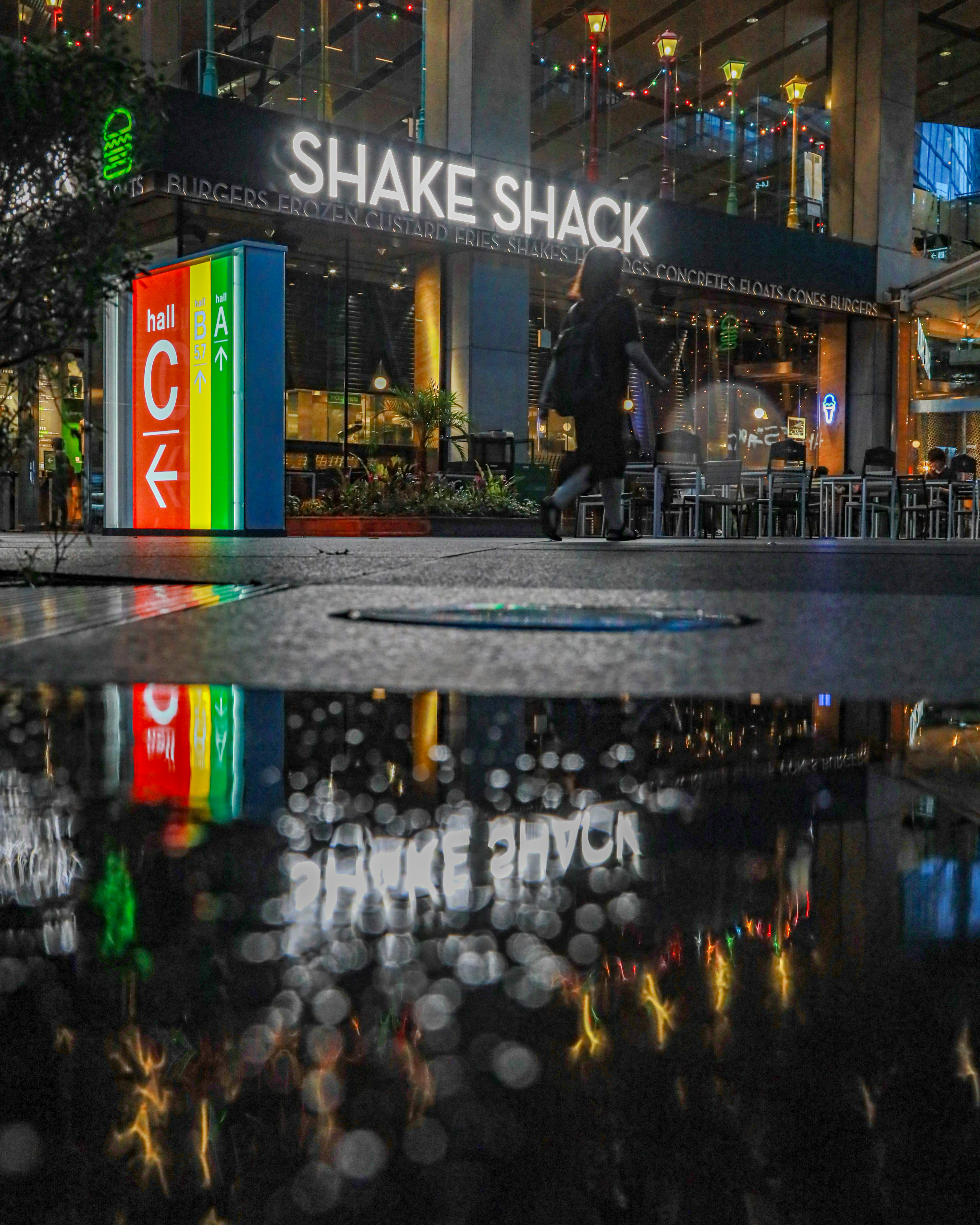 Vue nocturne du panneau Shake Shack reflété dans une flaque