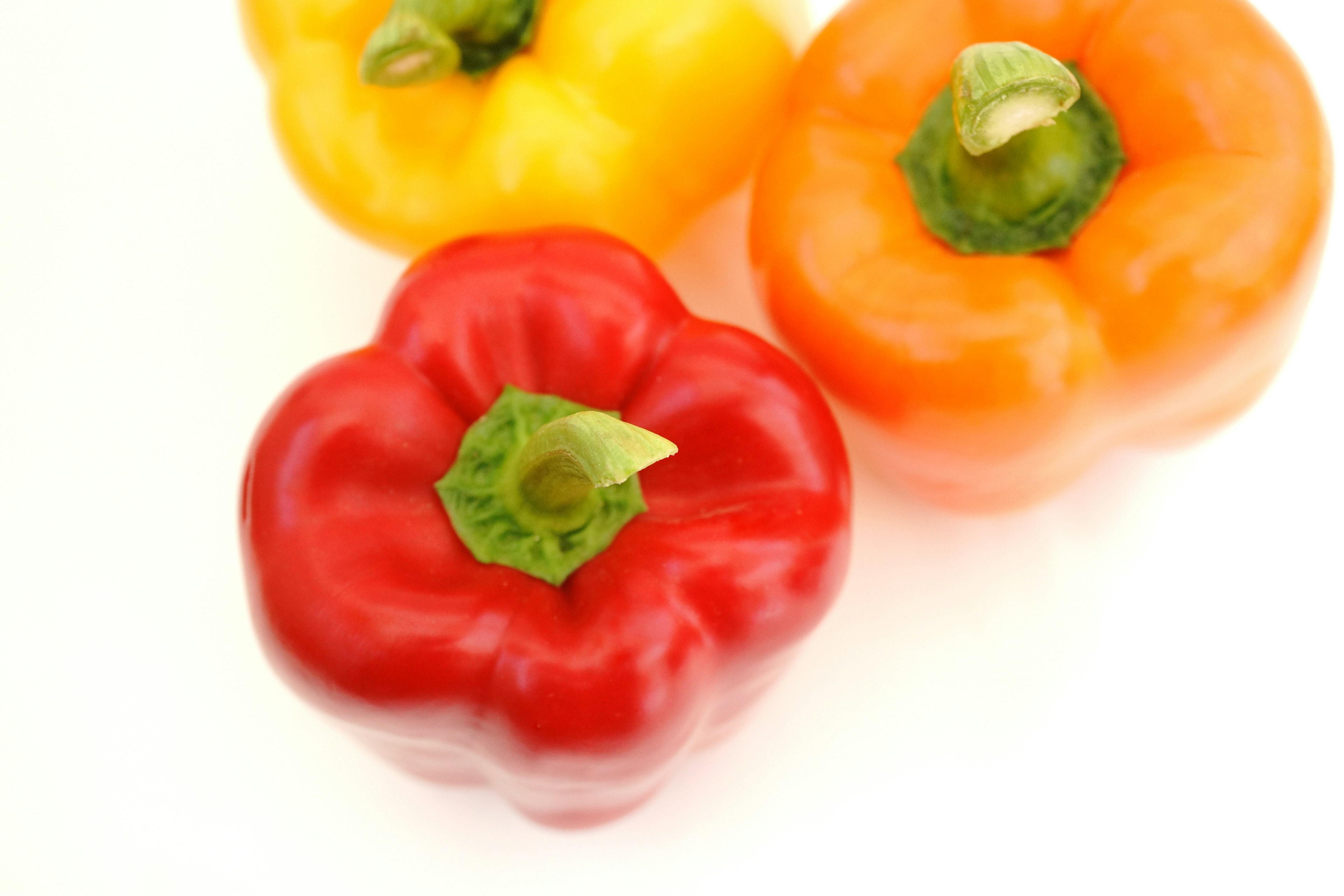 Vibrant red, orange, and yellow bell peppers arranged together