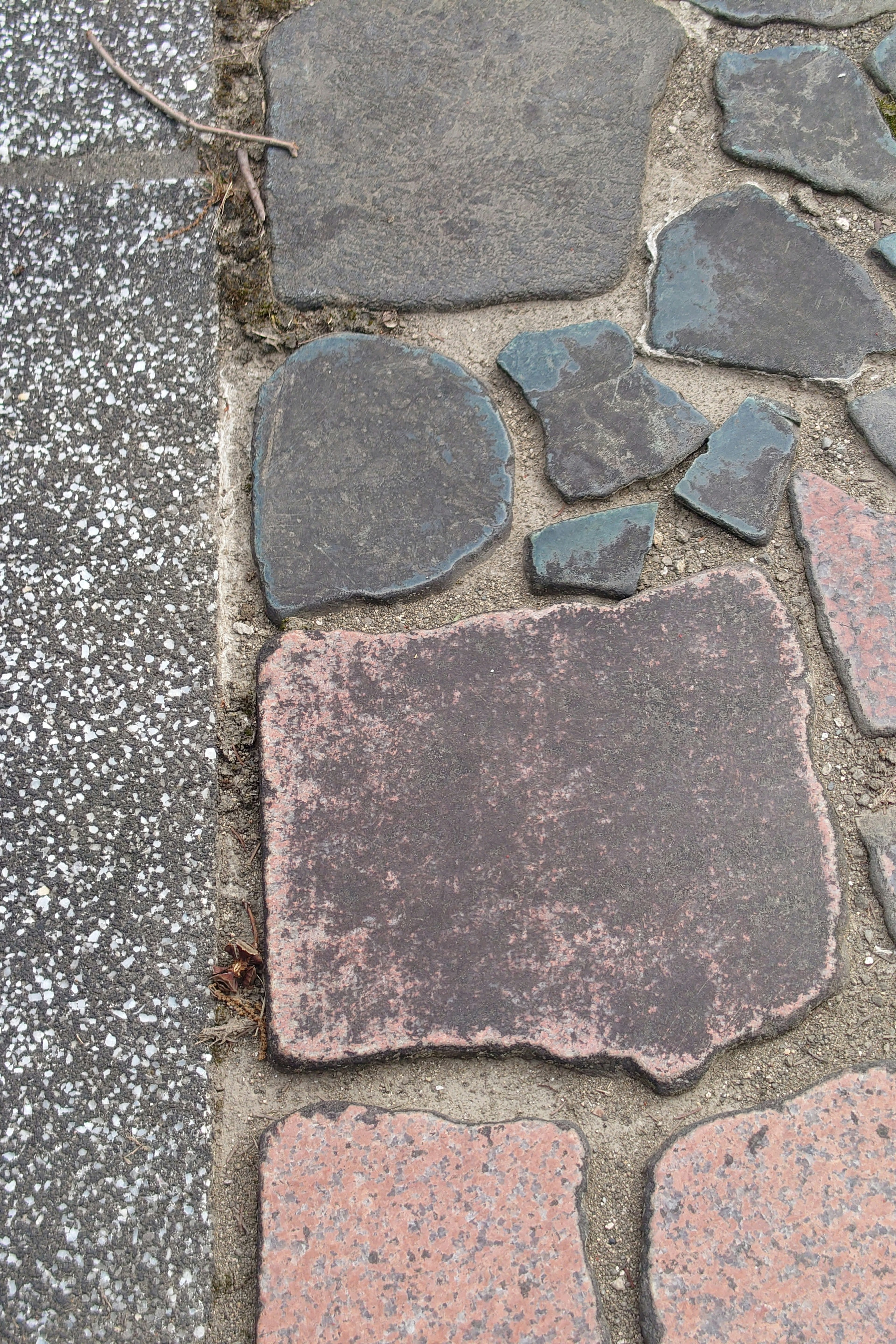 Section of a sidewalk featuring various colored and shaped stones