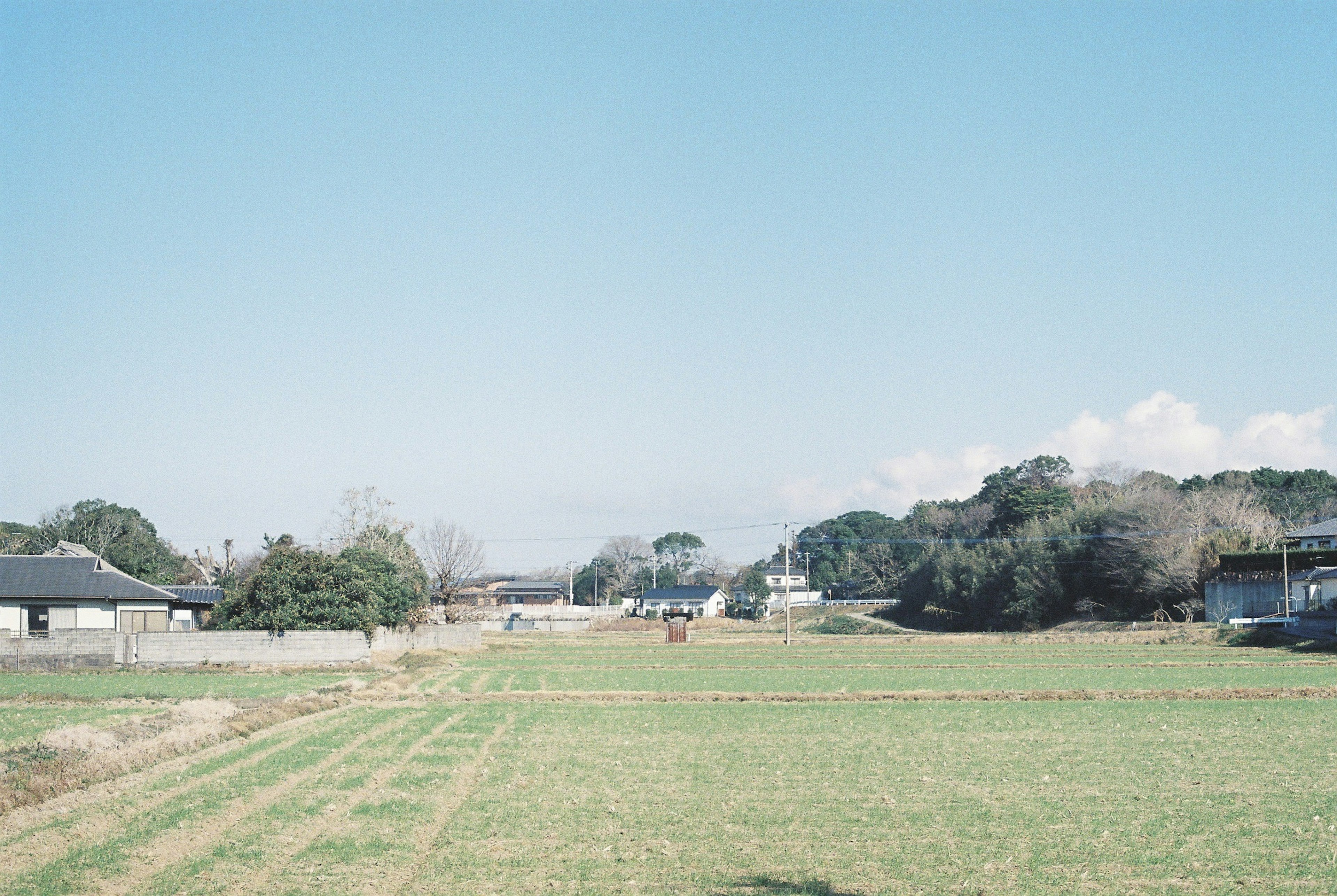 Paisaje rural bajo un cielo azul con casas y campos