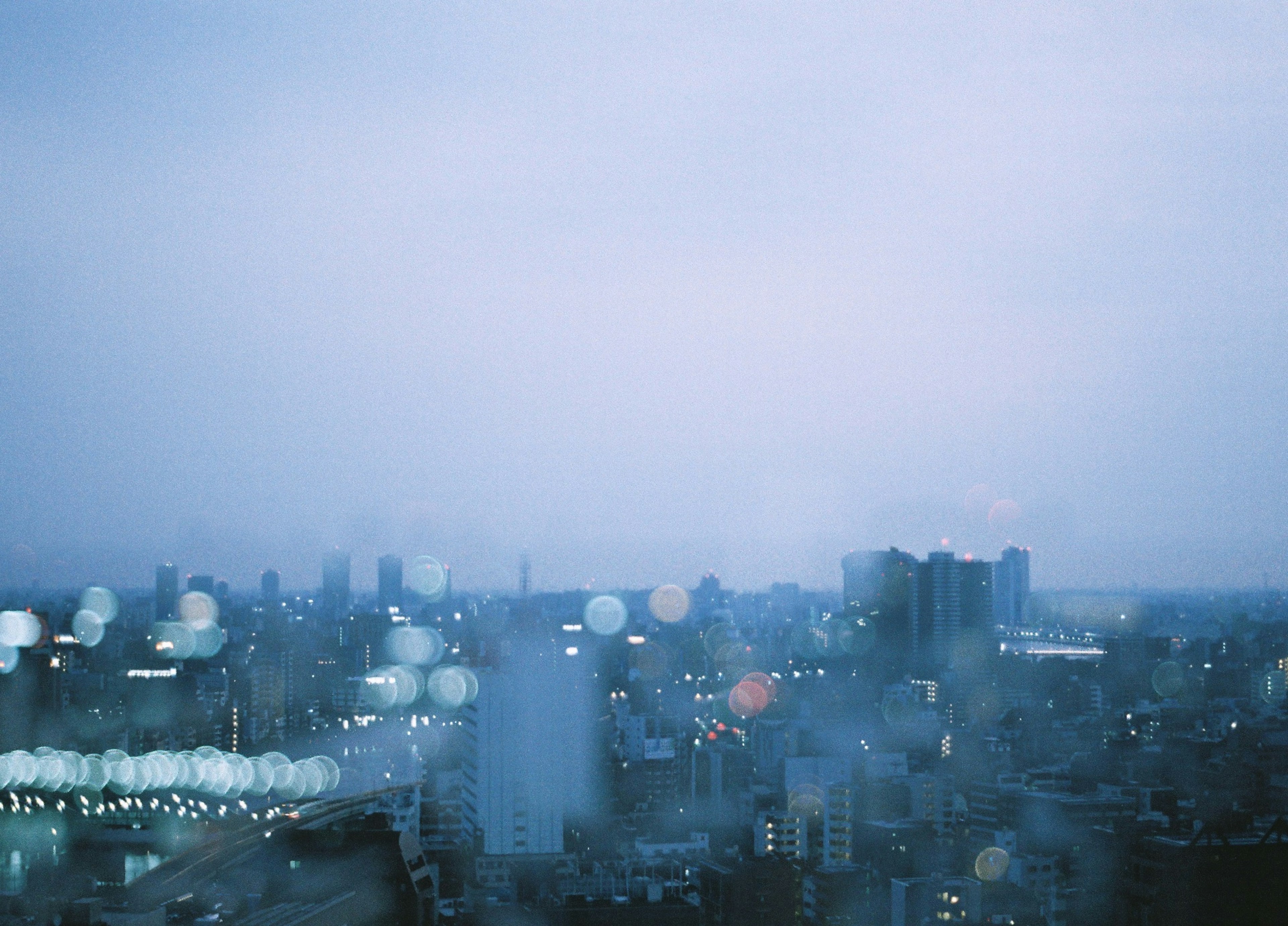 Foggy city skyline at night with blurred lights illuminating the buildings