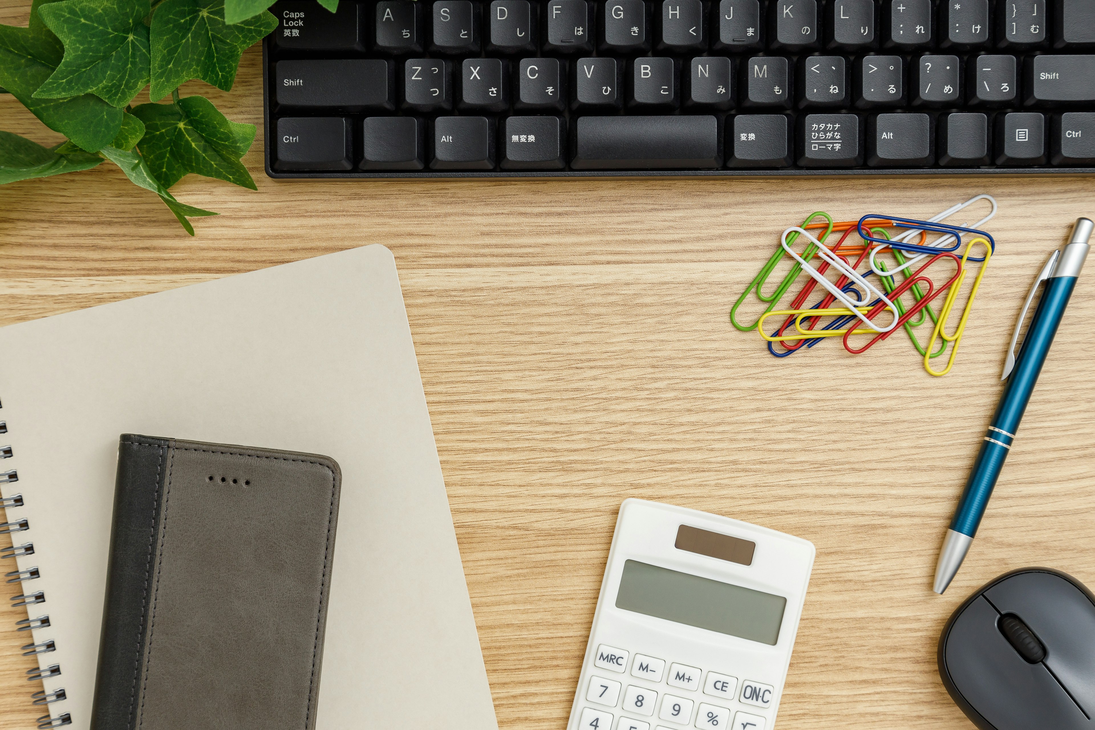 Un bureau en bois avec un clavier une calculatrice et des fournitures de bureau