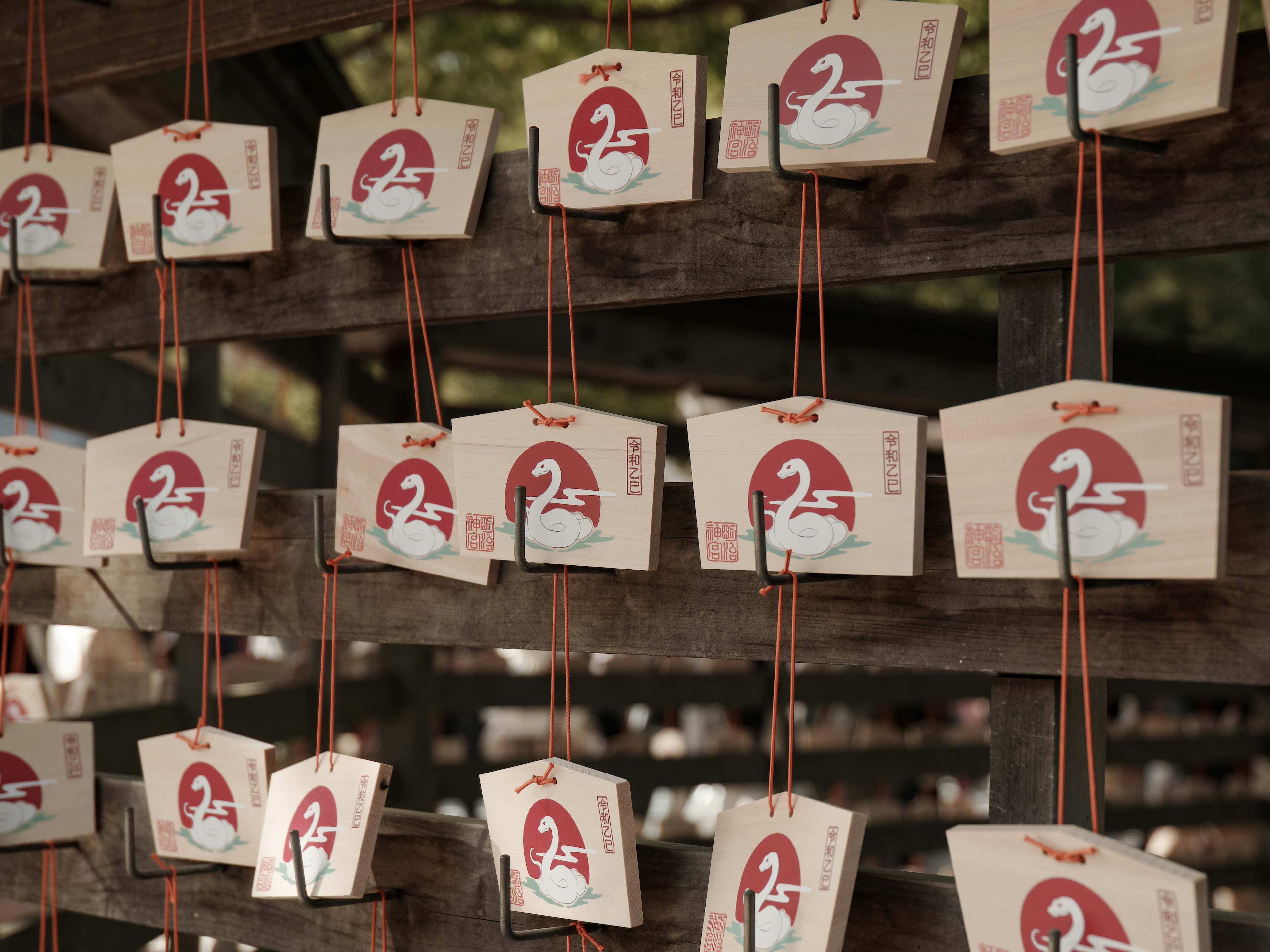 Wooden plaques with red designs hanging on a wooden rack