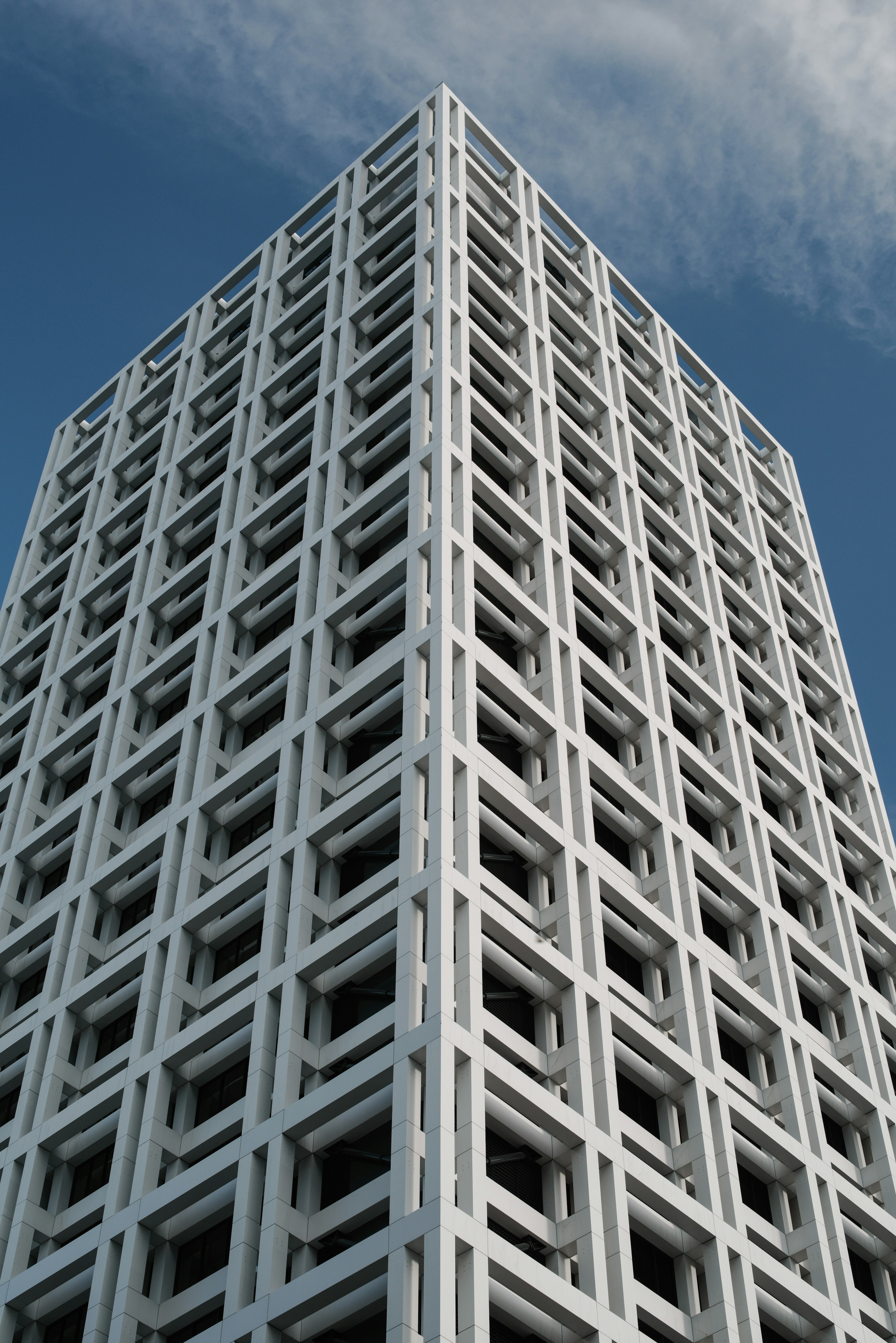 Image d'un coin d'un immeuble de grande hauteur en béton blanc mettant en valeur un design moderne et des motifs géométriques