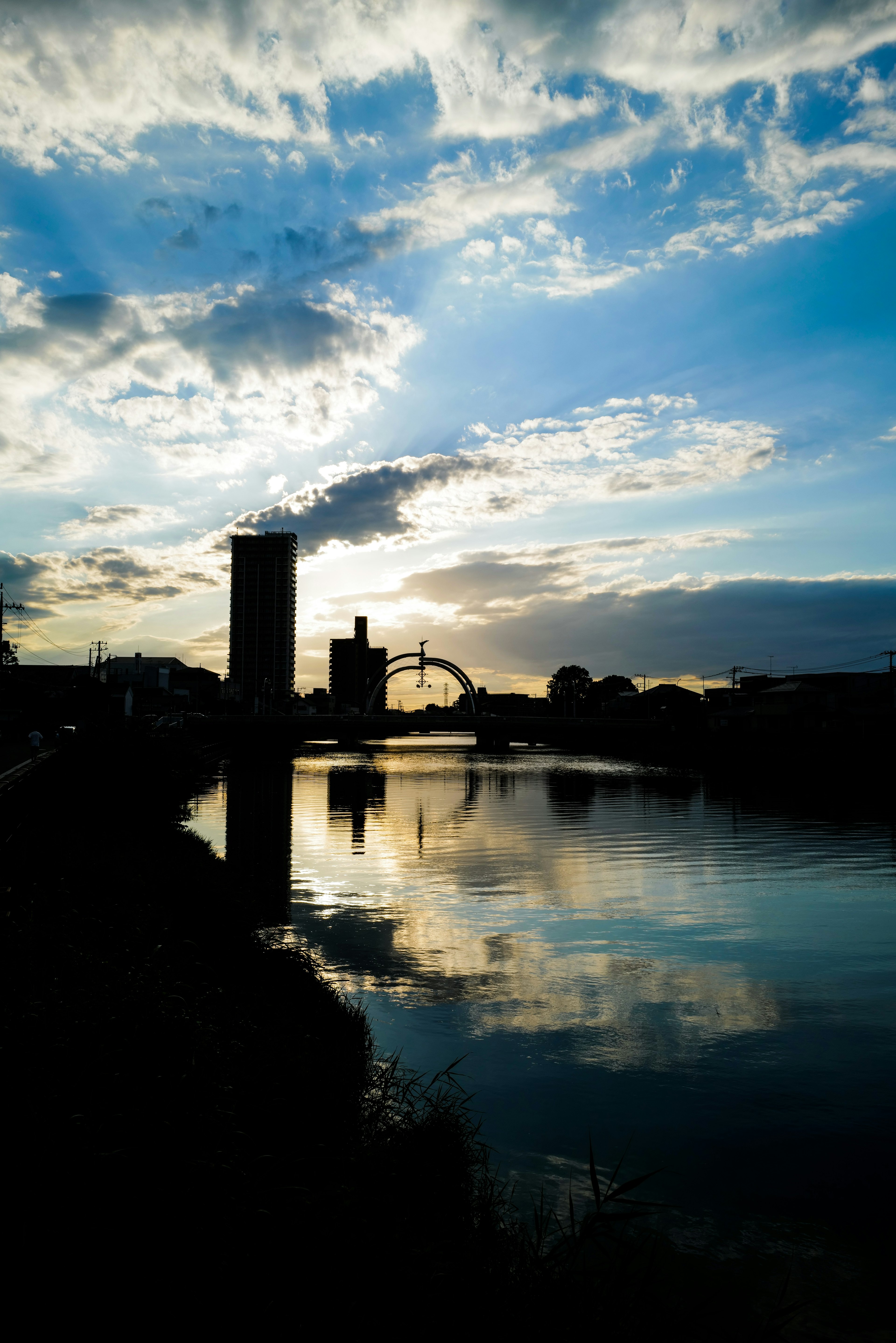 Silhouette of buildings against a sunset reflecting on the river