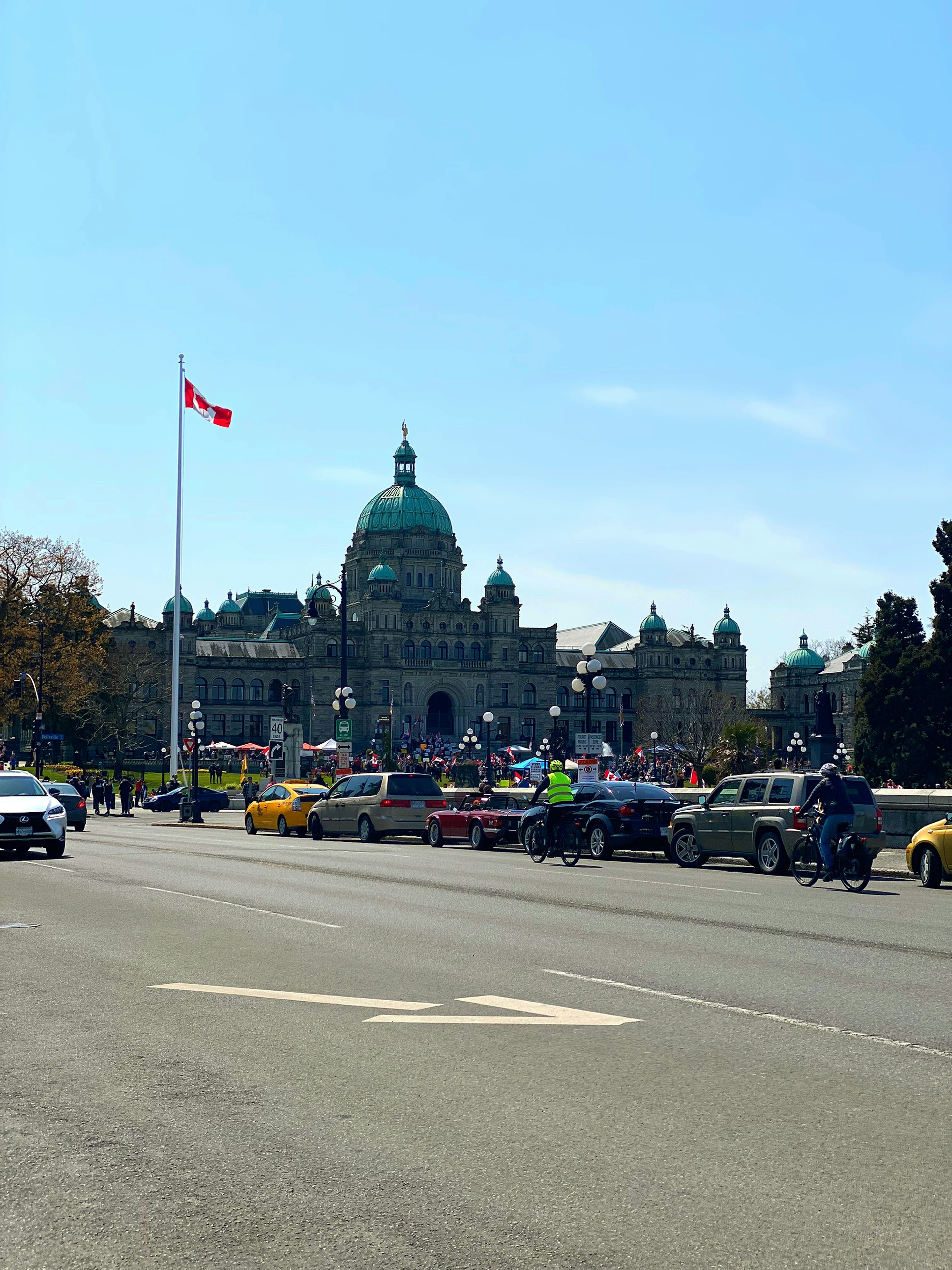 Vue des bâtiments du Parlement de la Colombie-Britannique avec le drapeau canadien et une rue animée