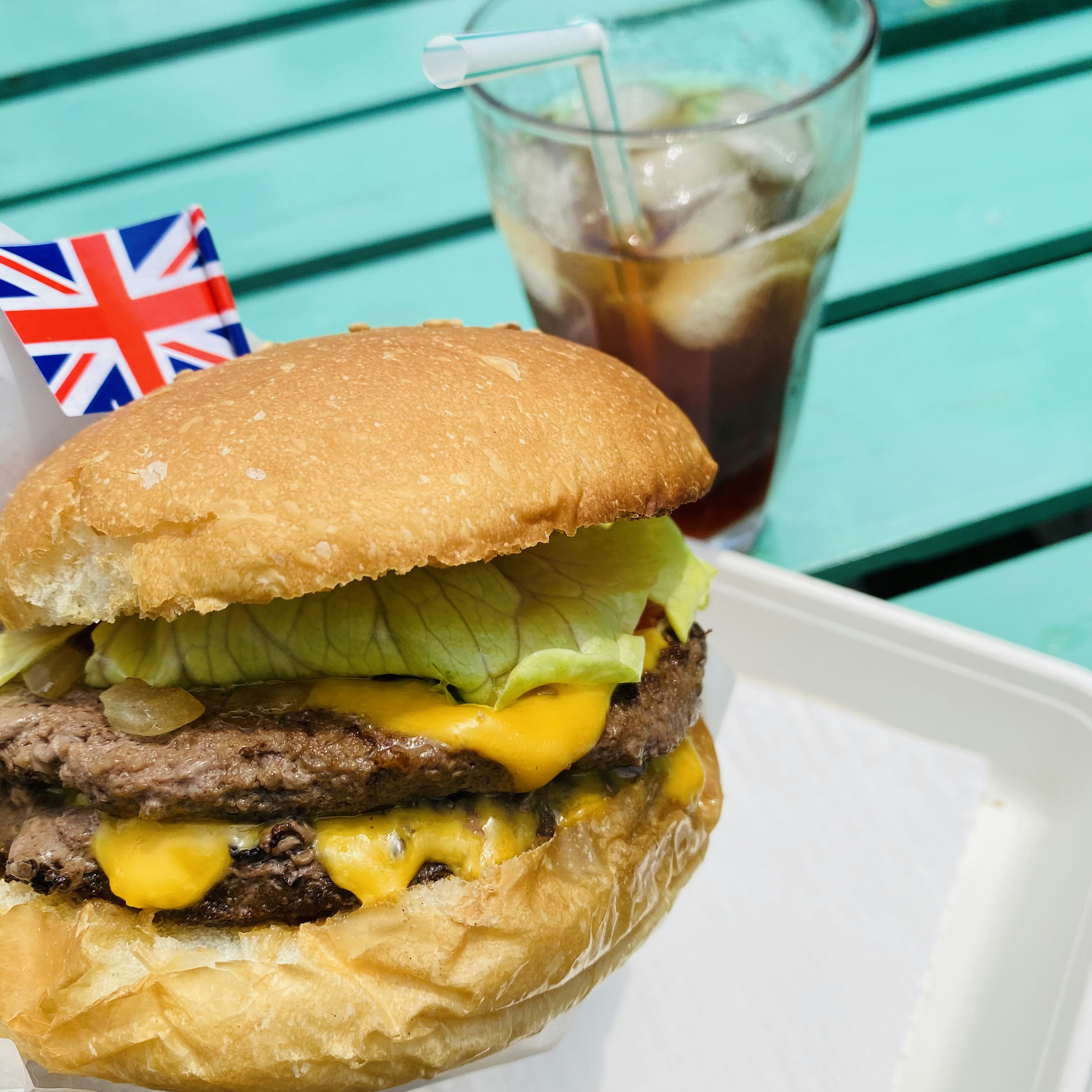 Hamburguesa con bandera británica y café helado sobre una mesa azul