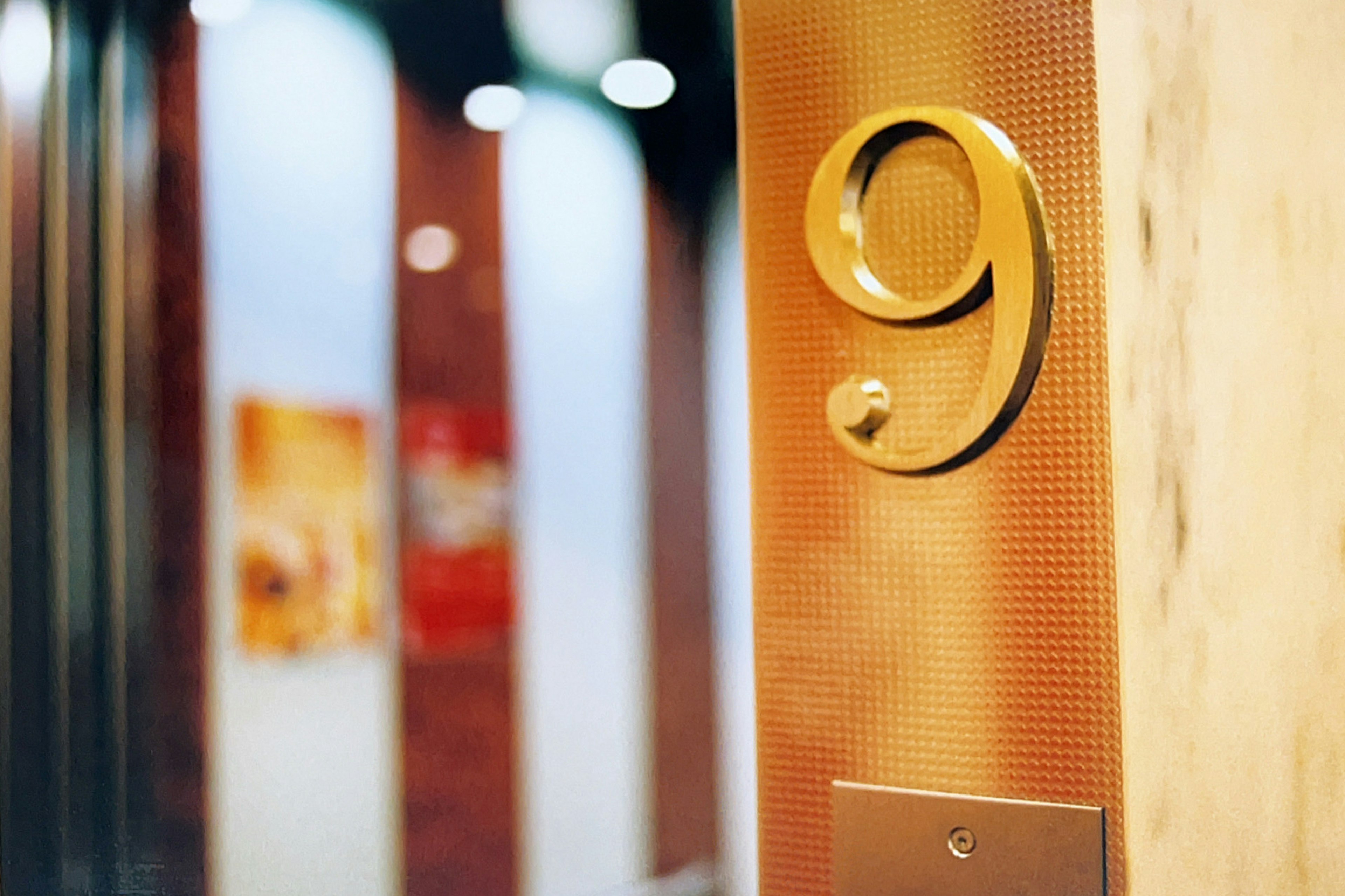 Elevator door with the number 9 in gold and decorative background