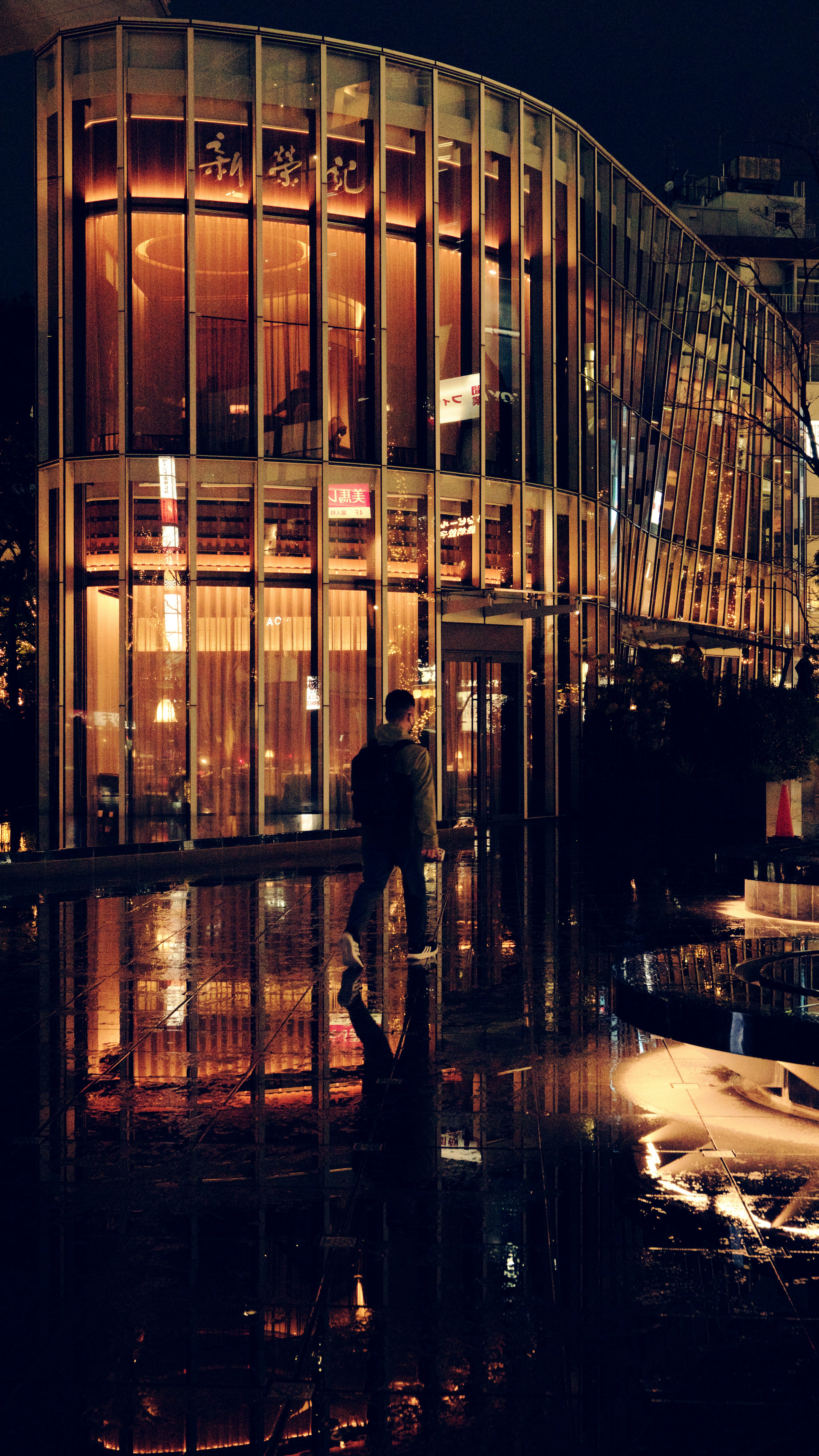 Fachada de un edificio moderno iluminado por la noche con reflejos