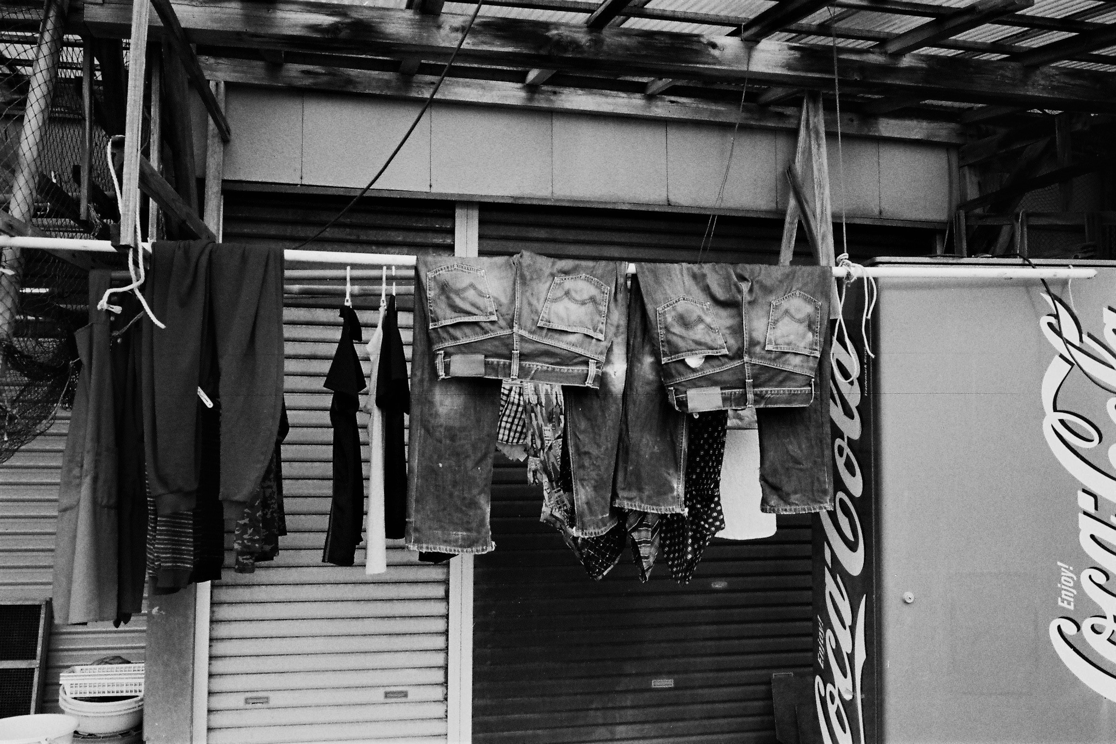 Escena al aire libre con ropa colgada jeans y camisas expuestas letrero de Coca-Cola visible