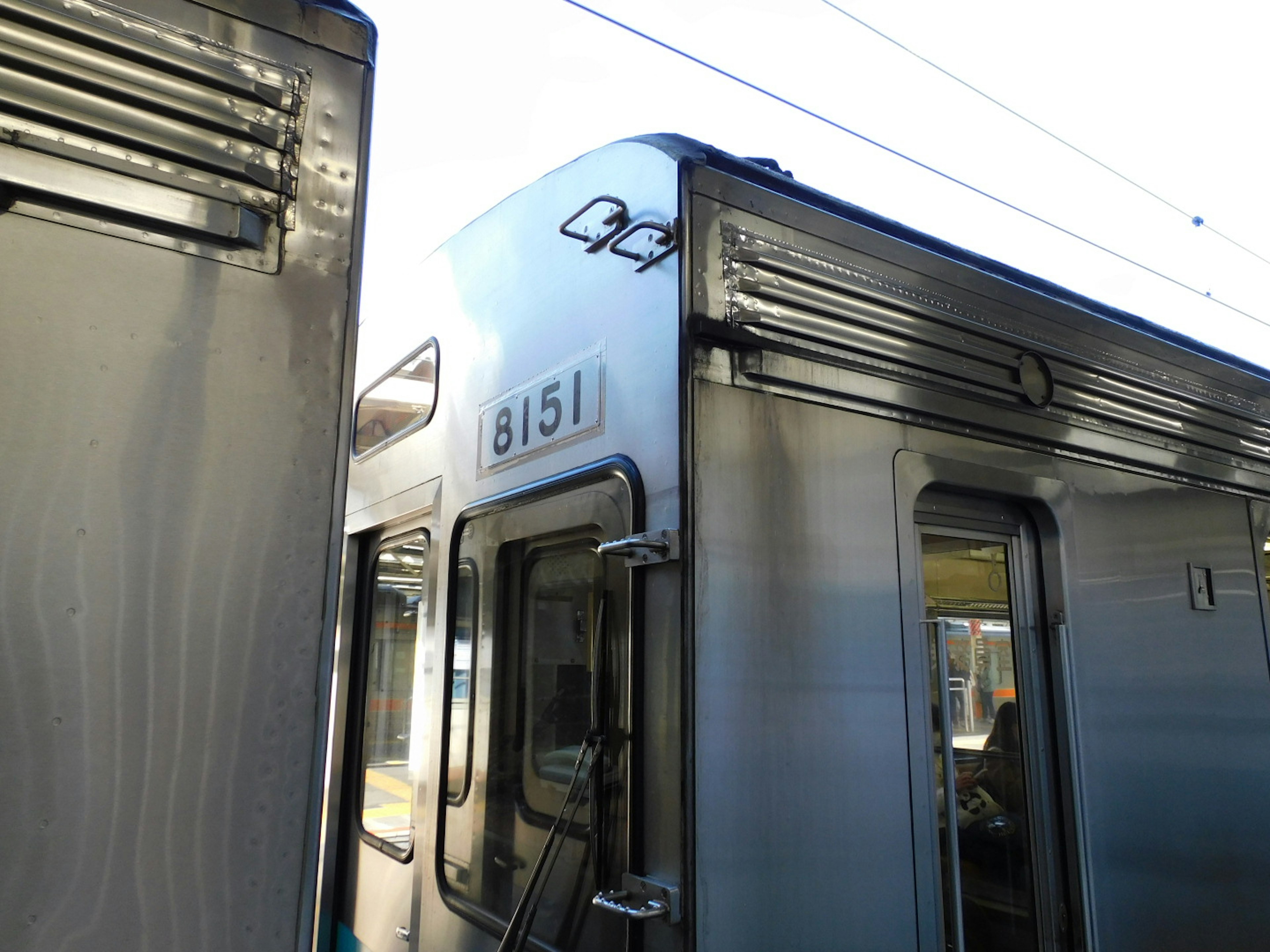 銀色の電車の側面と番号8151が見える