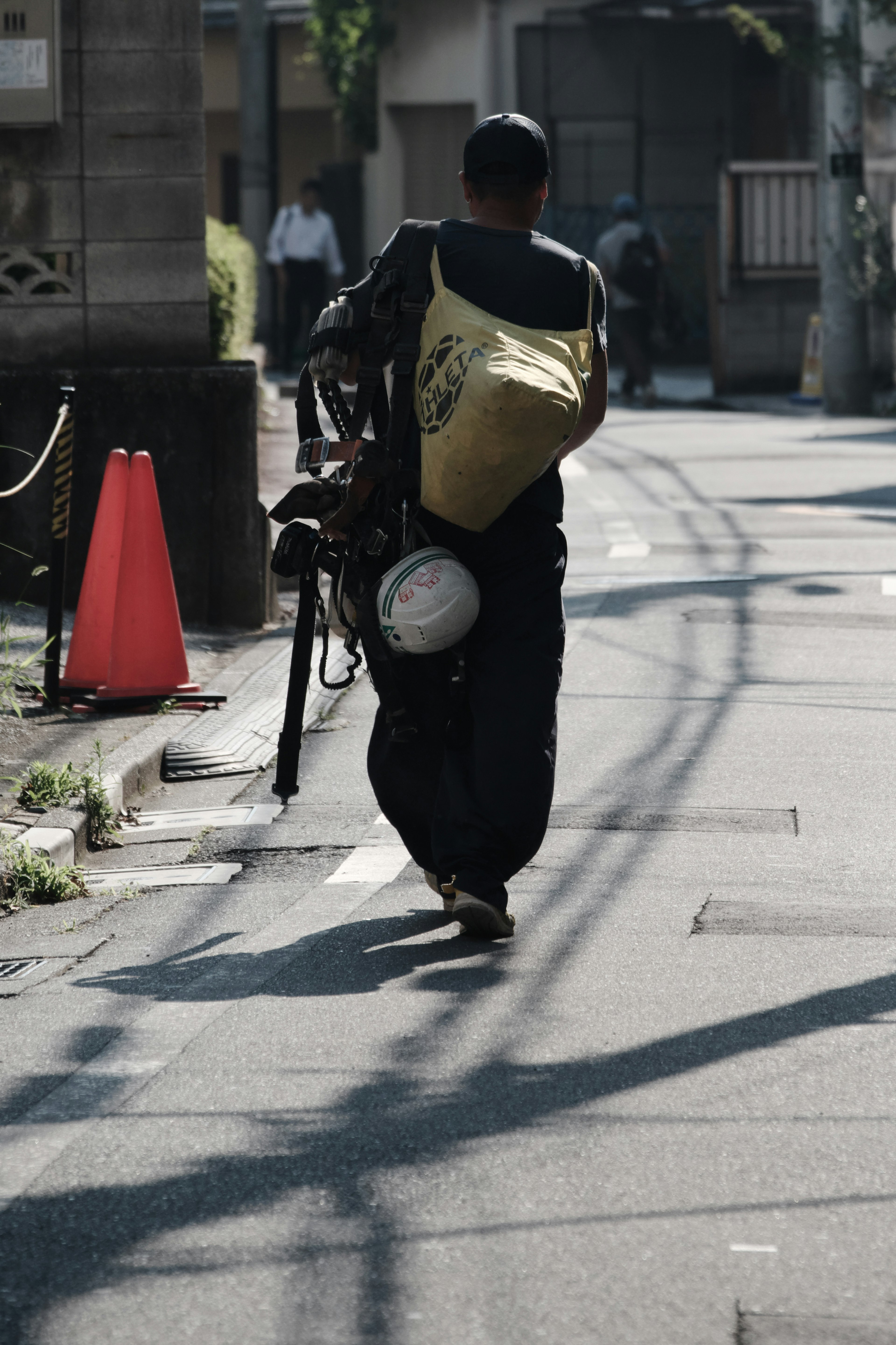 A man in black clothing walking with a motorcycle in an urban setting