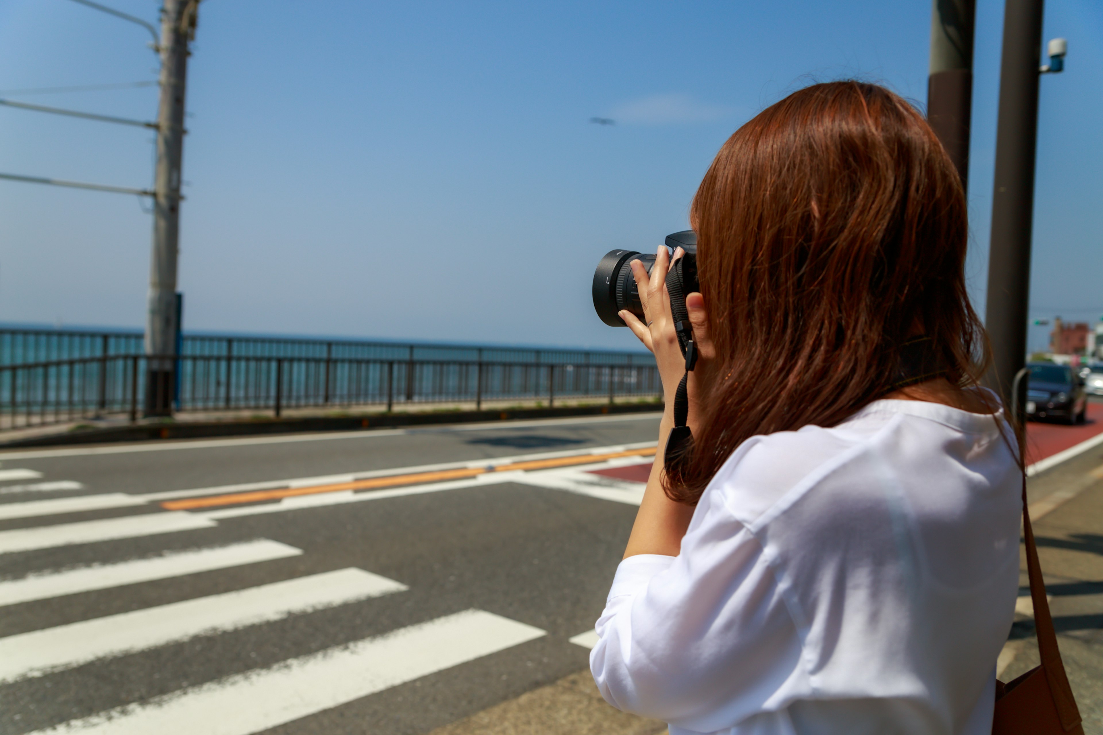 Eine Frau fotografiert das Meer mit einer Kamera an einem sonnigen Tag