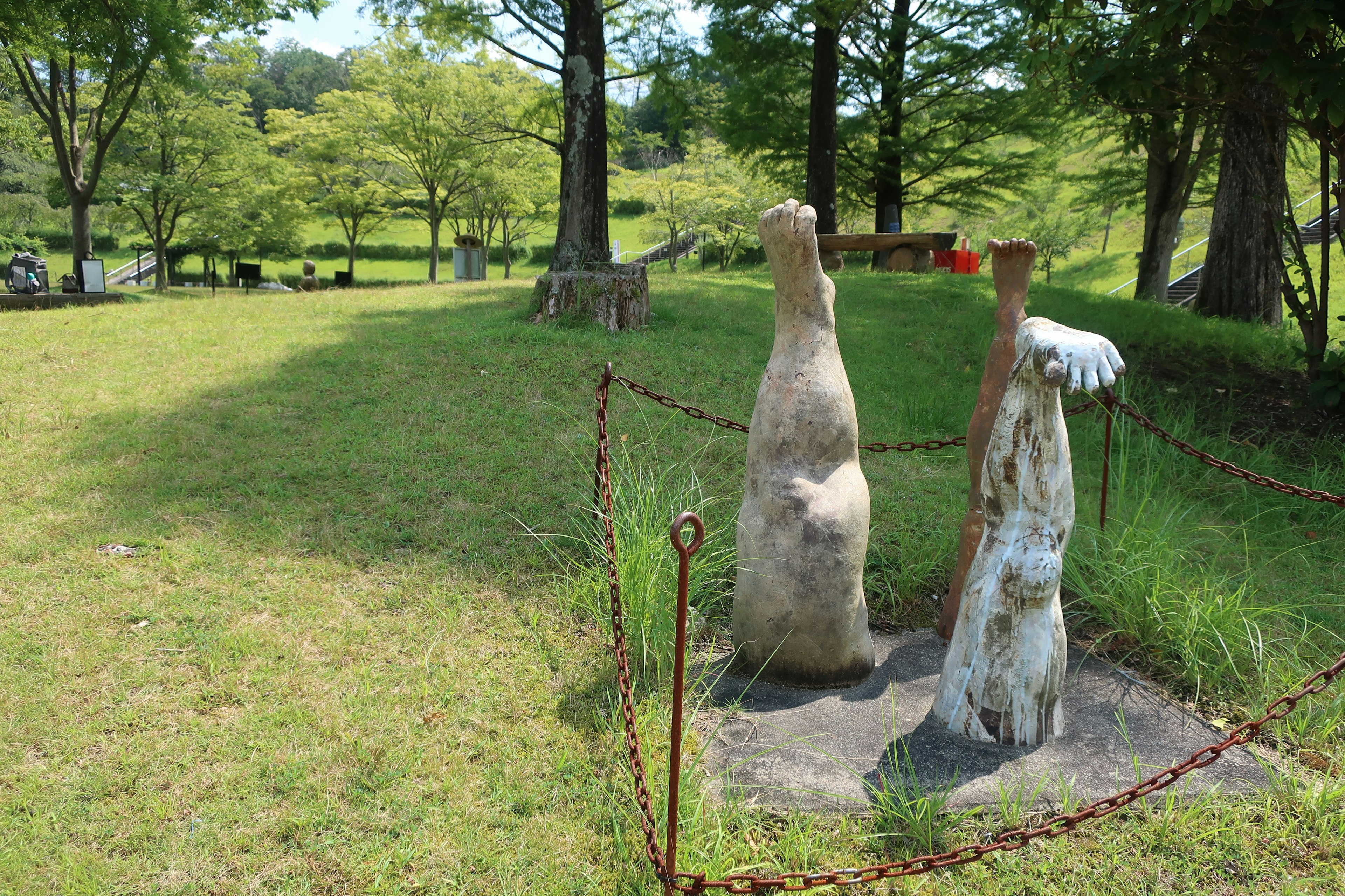 Deux sculptures en pierre se tenant sur l'herbe entourées d'arbres et de verdure