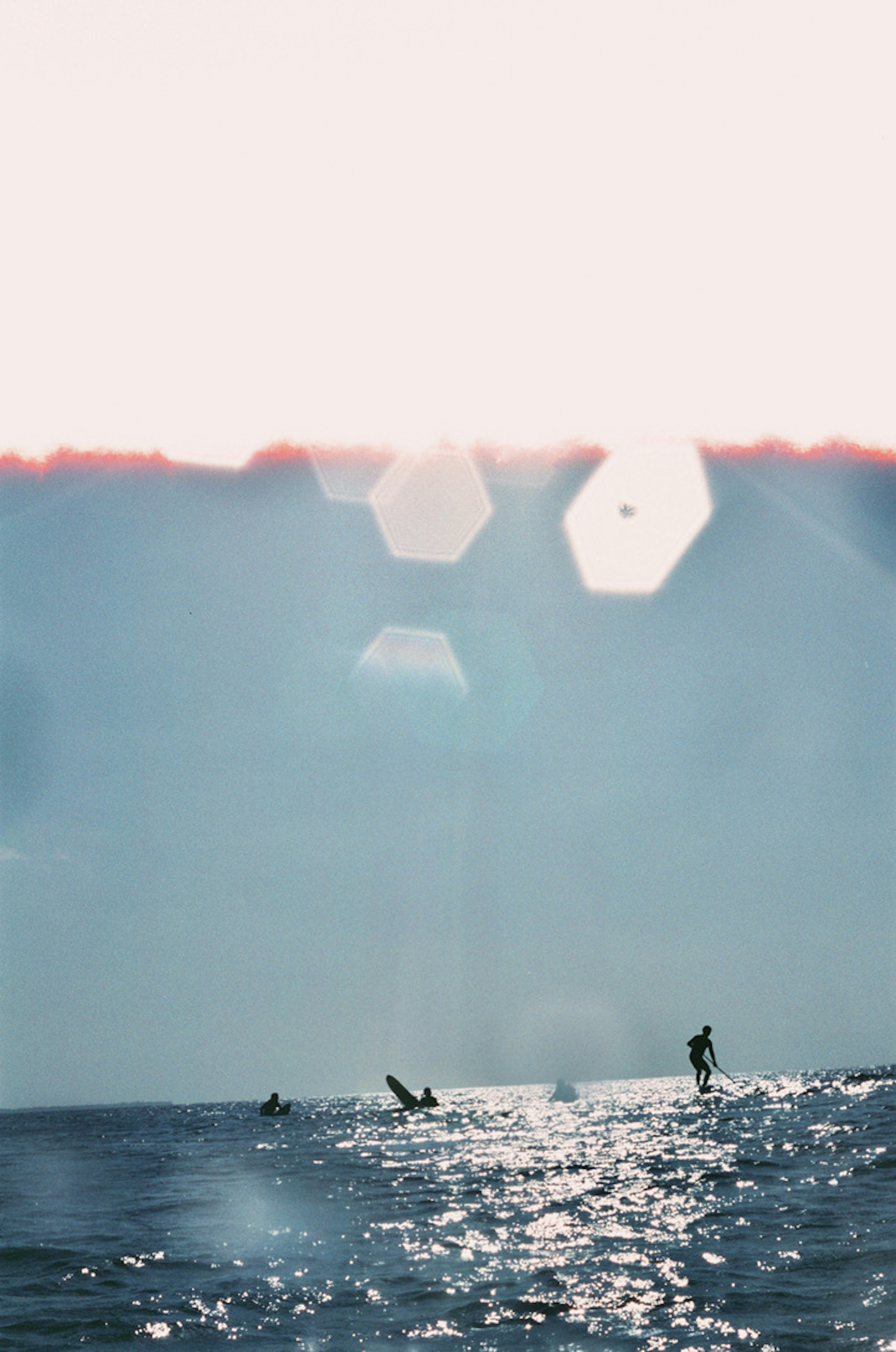 Silhouetten von Menschen, die auf dem Ozean surfen, mit schimmernden Wasserreflexionen