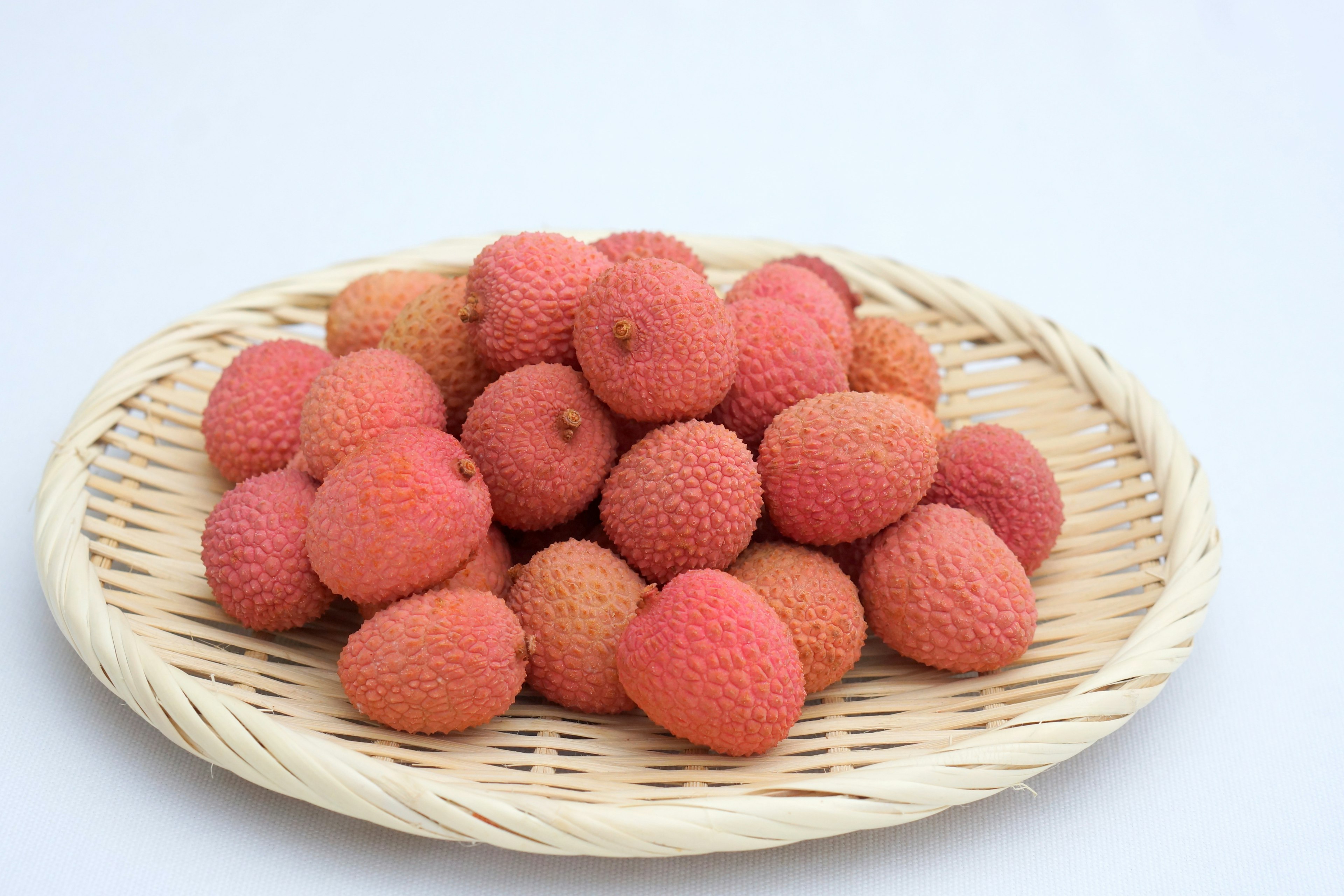 Fresh lychee fruits arranged in a woven basket