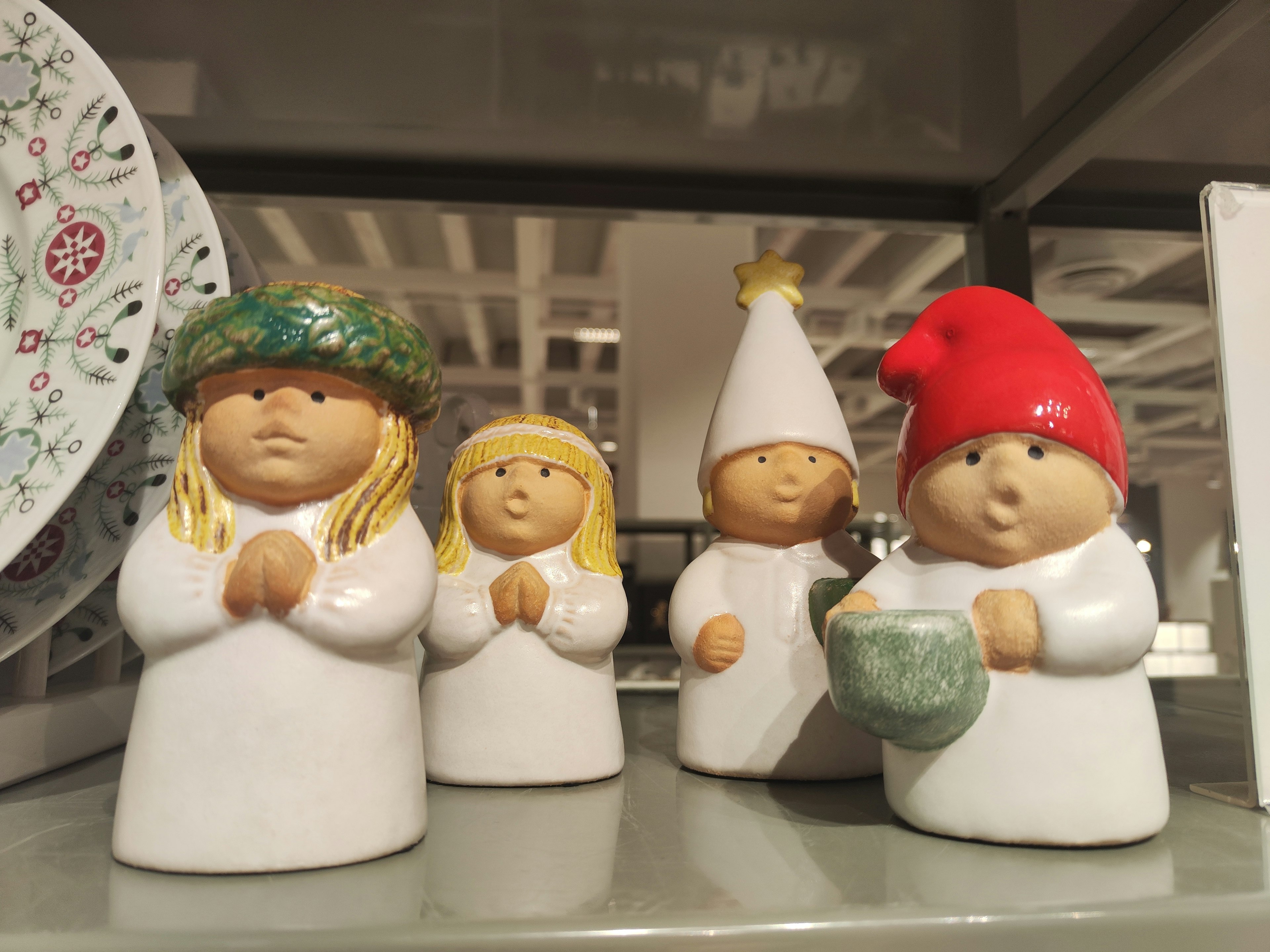 Four cute ceramic figurines standing with a colorful plate in the background