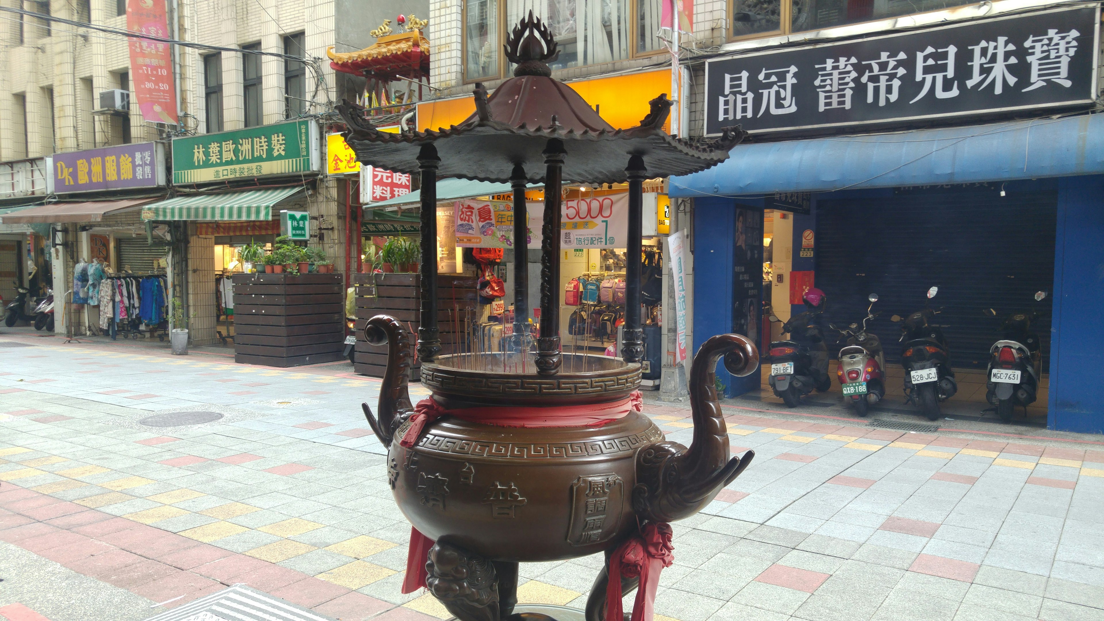 Traditional incense burner in the city center with surrounding shops