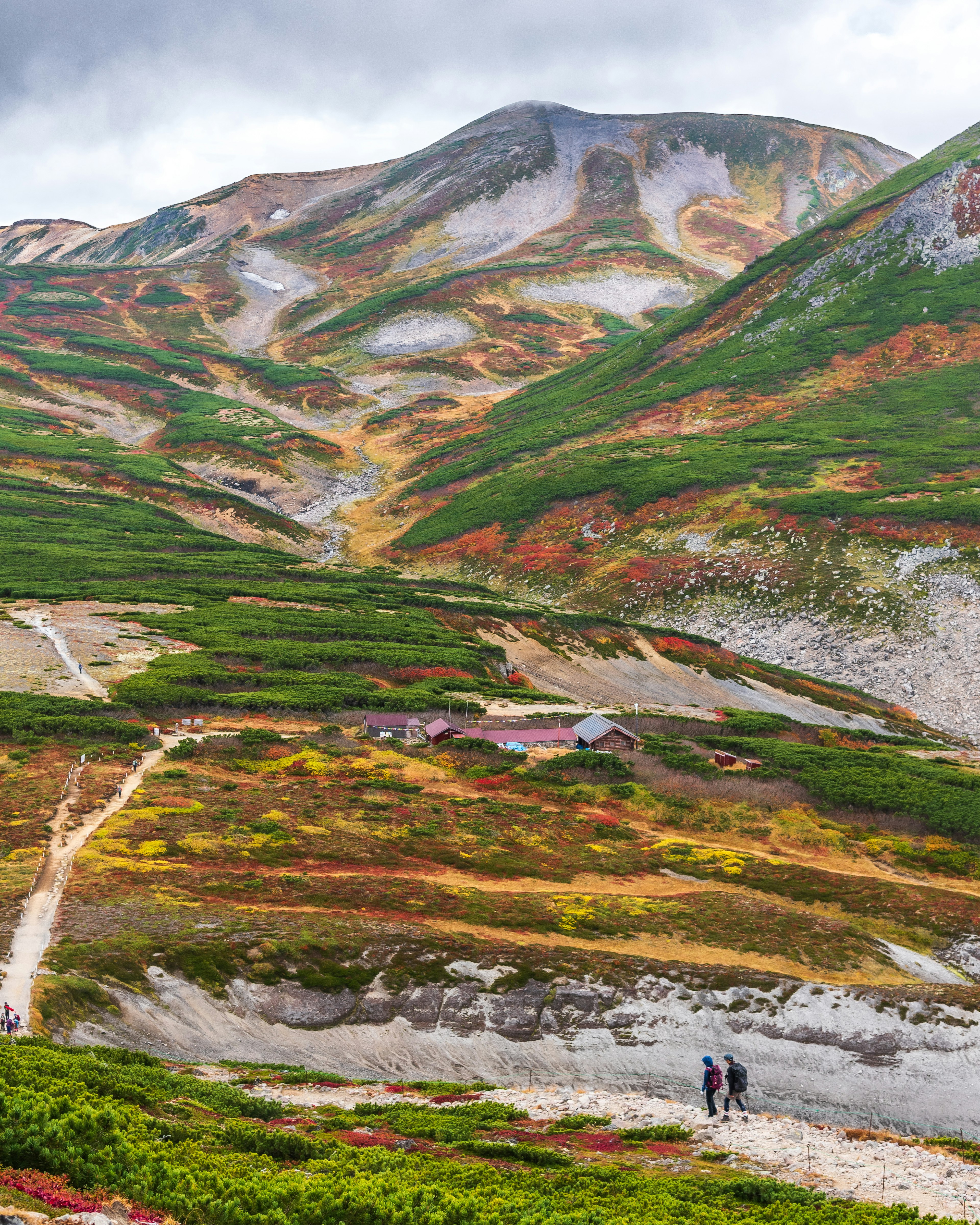 Paisaje escénico con montañas coloridas y excursionistas en un sendero