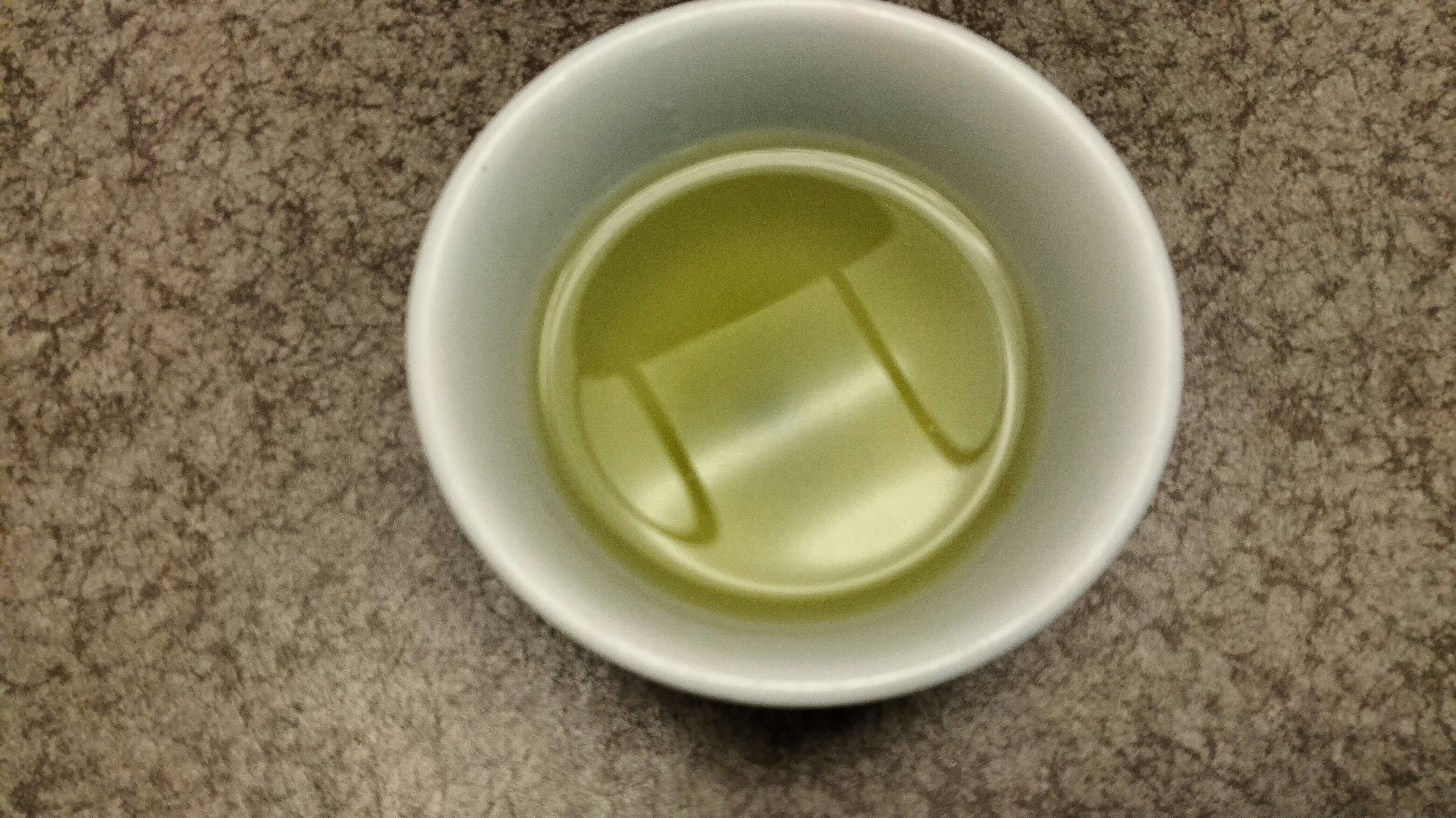 A white cup containing a light green liquid