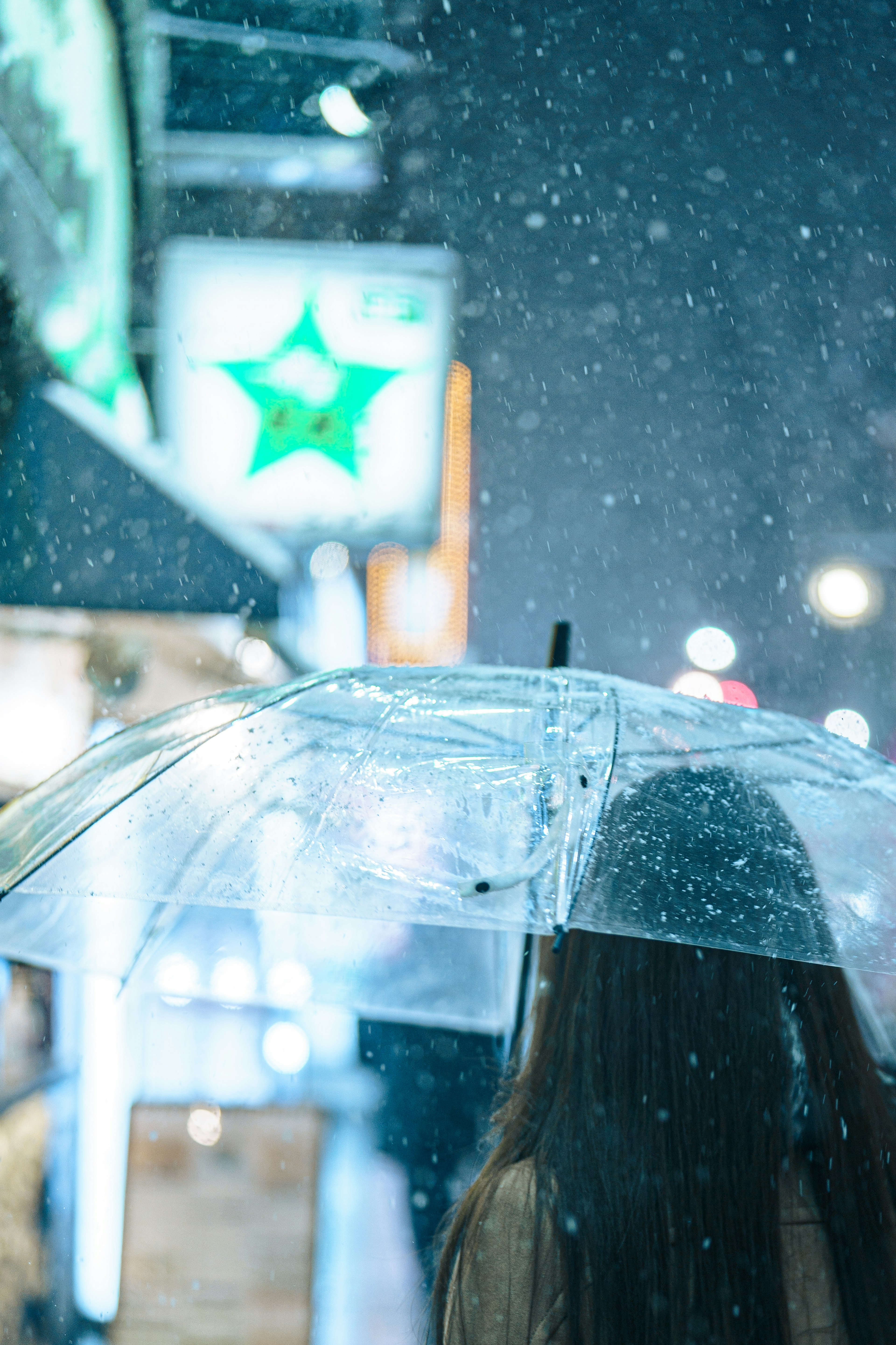 Eine Frau mit einem transparenten Regenschirm, die in einer verschneiten Stadtstraße geht