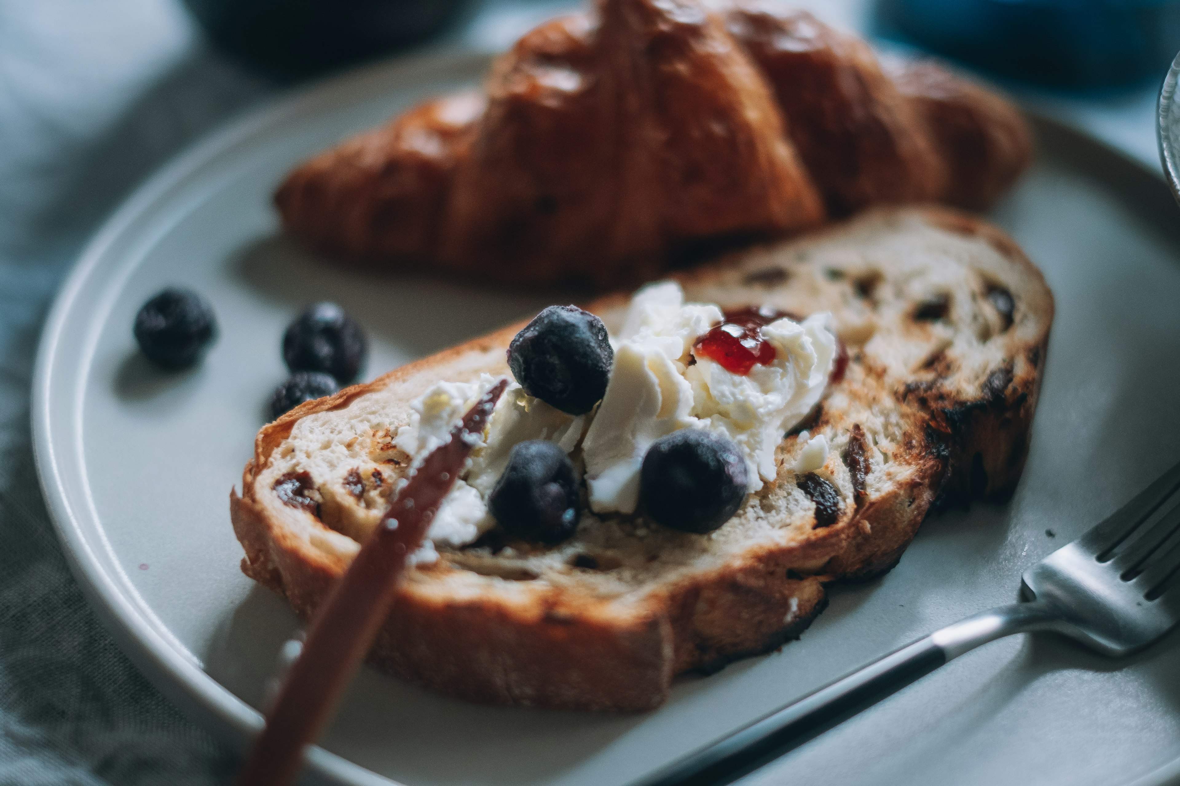 Piatto della colazione con toast guarnito di crema di formaggio e mirtilli