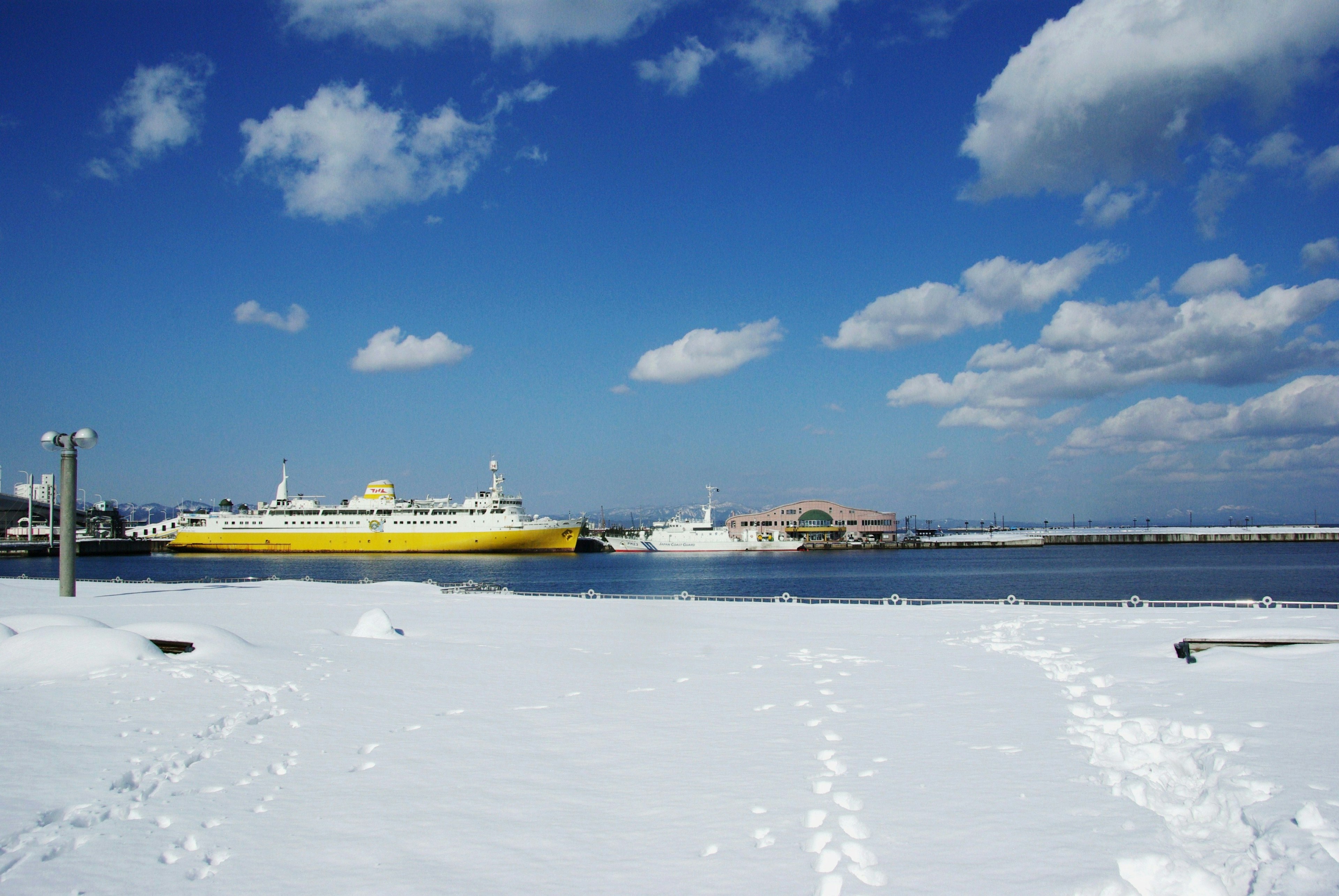 Ferry giallo che naviga su una spiaggia innevata sotto un cielo blu