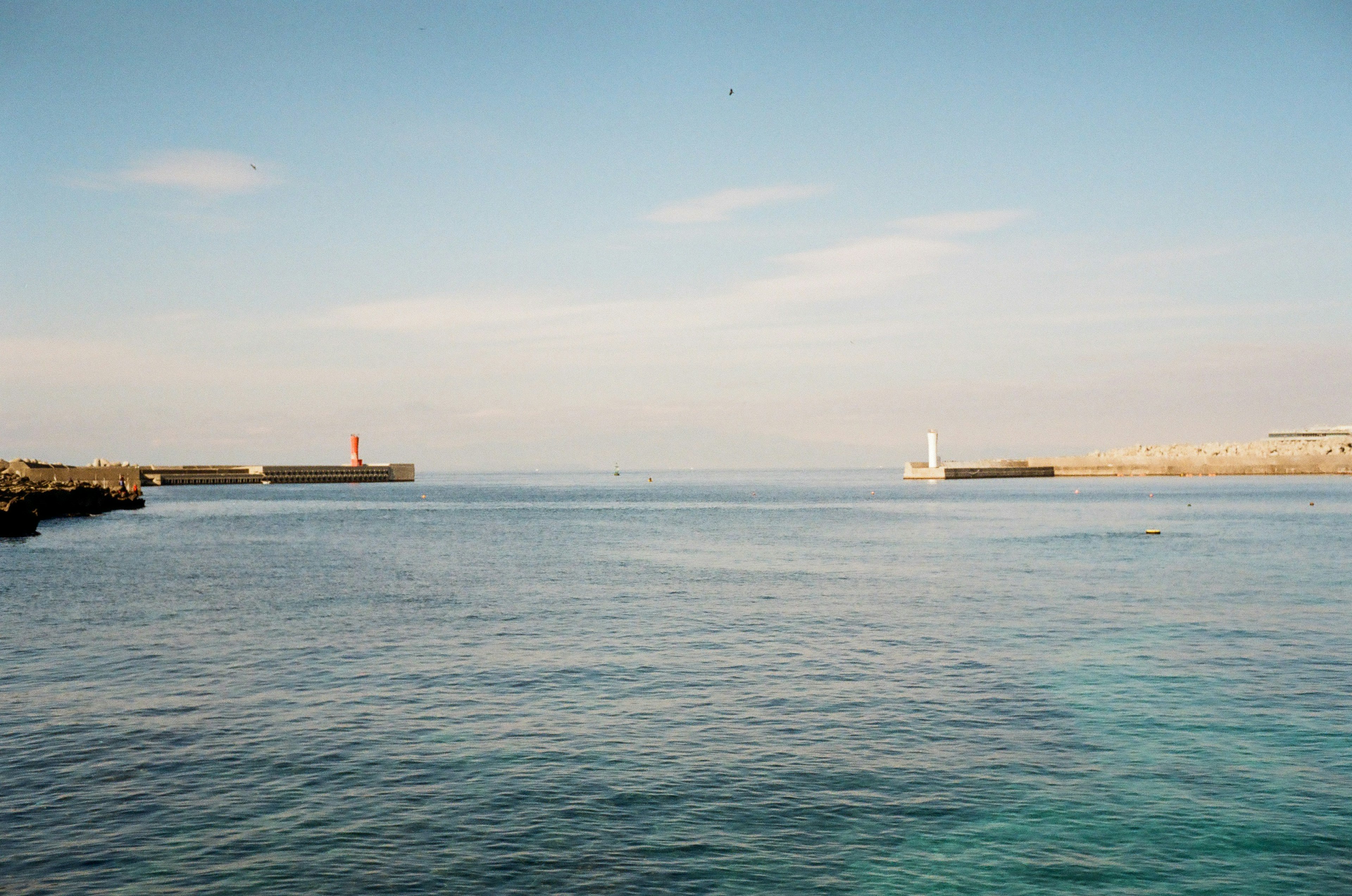 Panoramablick auf ein ruhiges blaues Meer mit roten und weißen Leuchttürmen in der Ferne