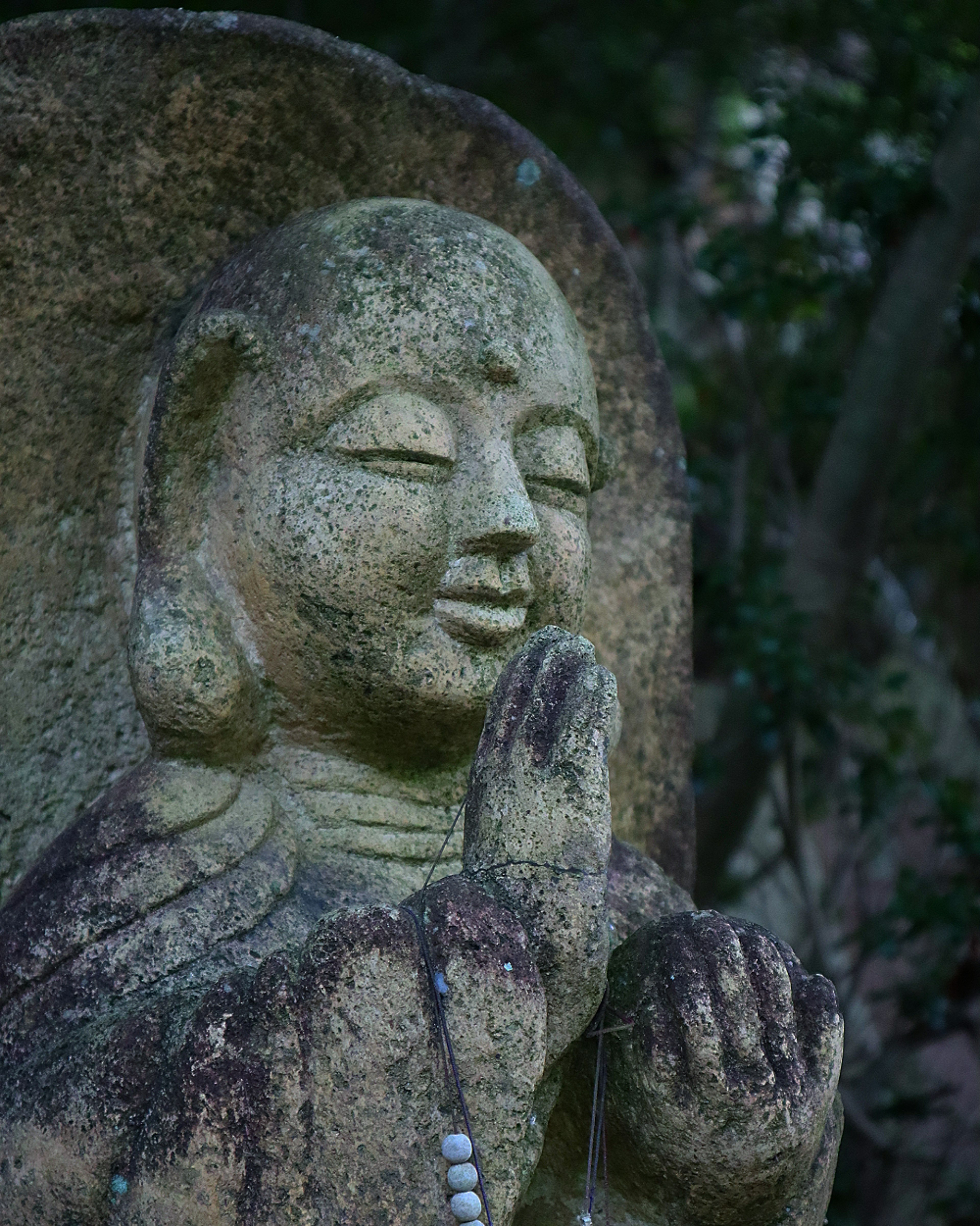 Stein-Buddha-Statue mit ruhigem Ausdruck und gefalteten Händen