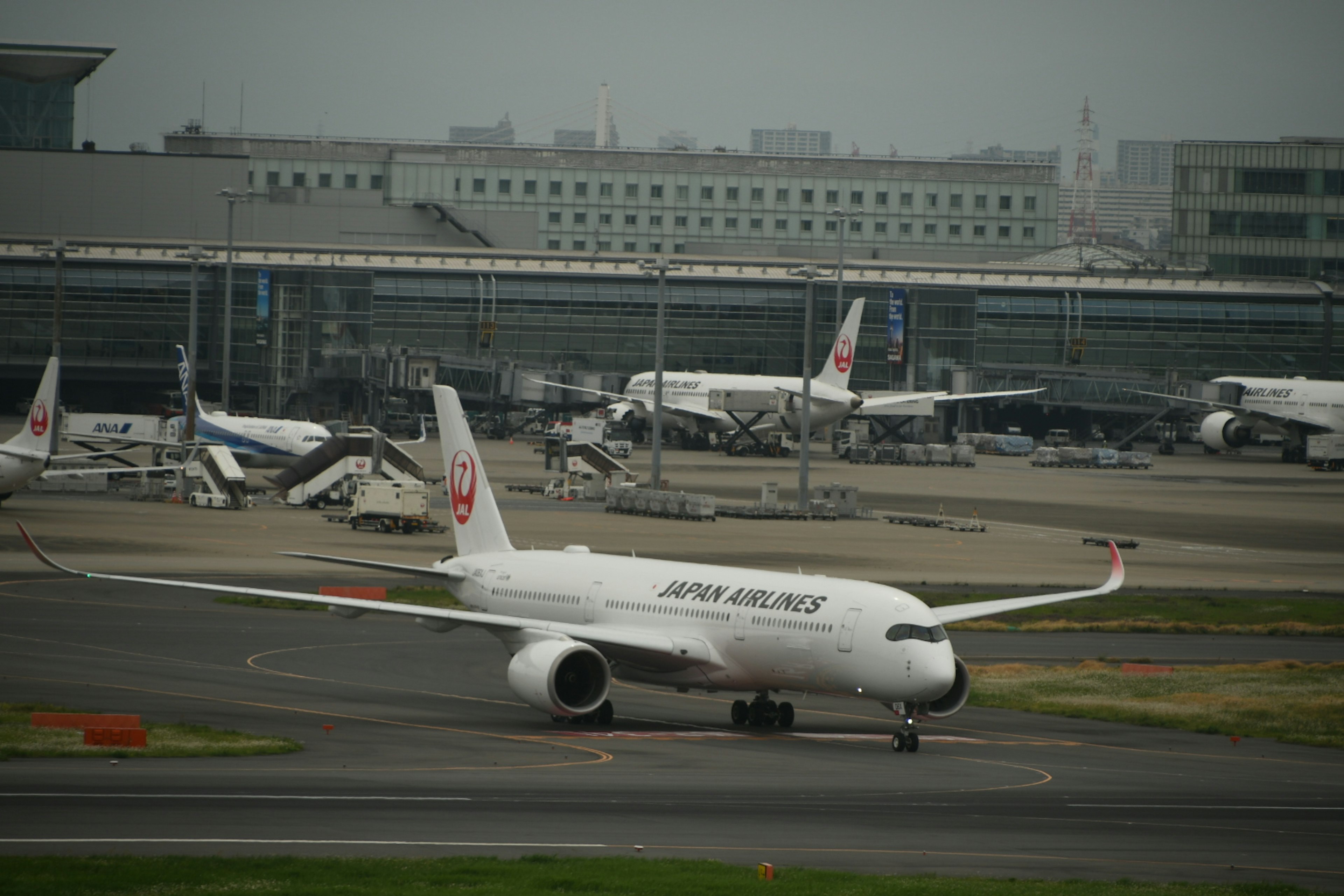 Pesawat Japan Airlines yang sedang taxi di bandara dengan pesawat lain di latar belakang