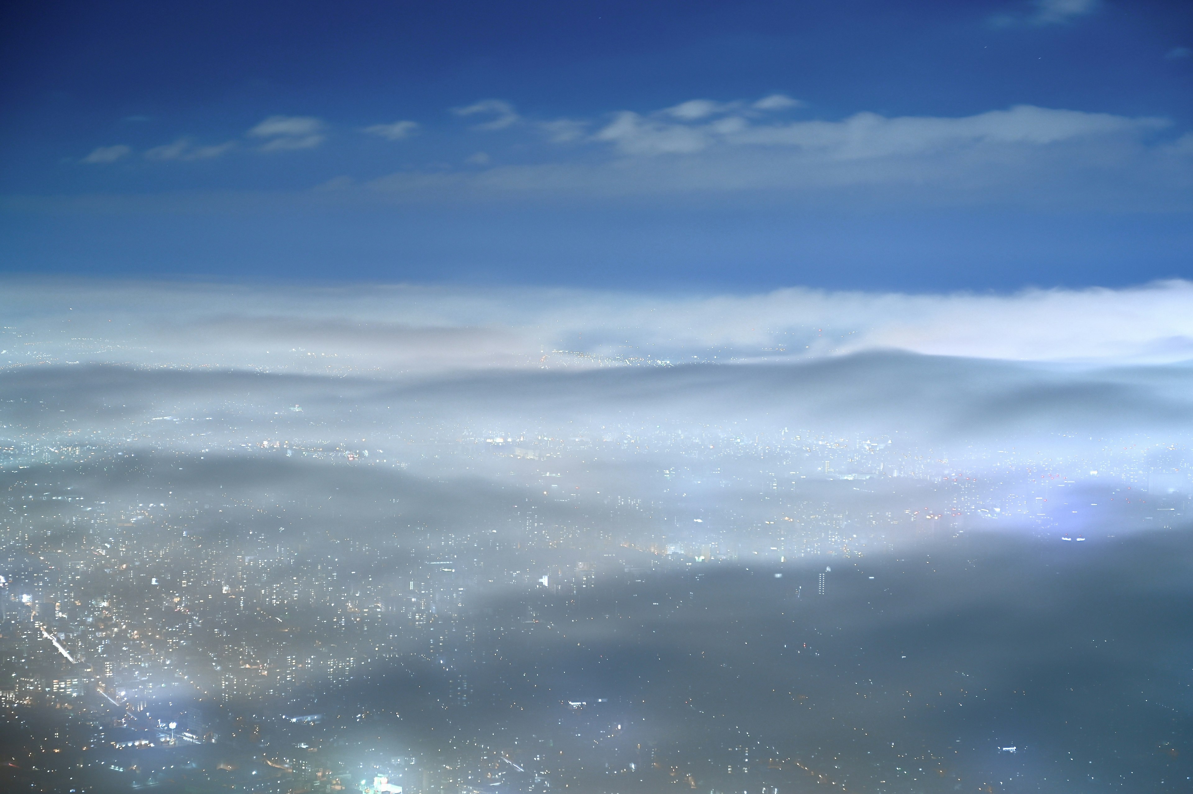 Pemandangan panorama kota di malam hari di bawah langit biru dan awan