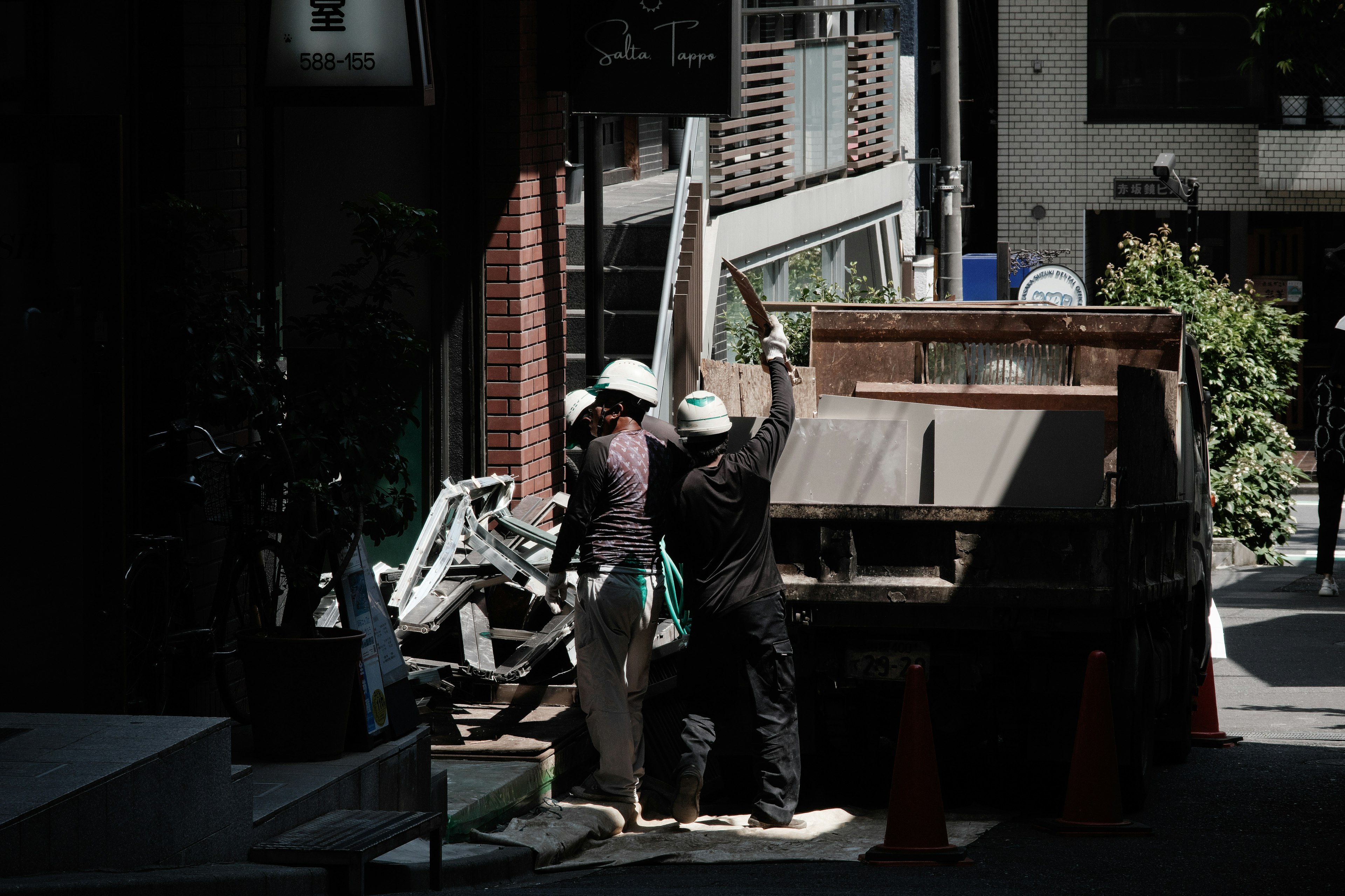 作業服を着た二人の作業員がトラックに資材を積み込む光景