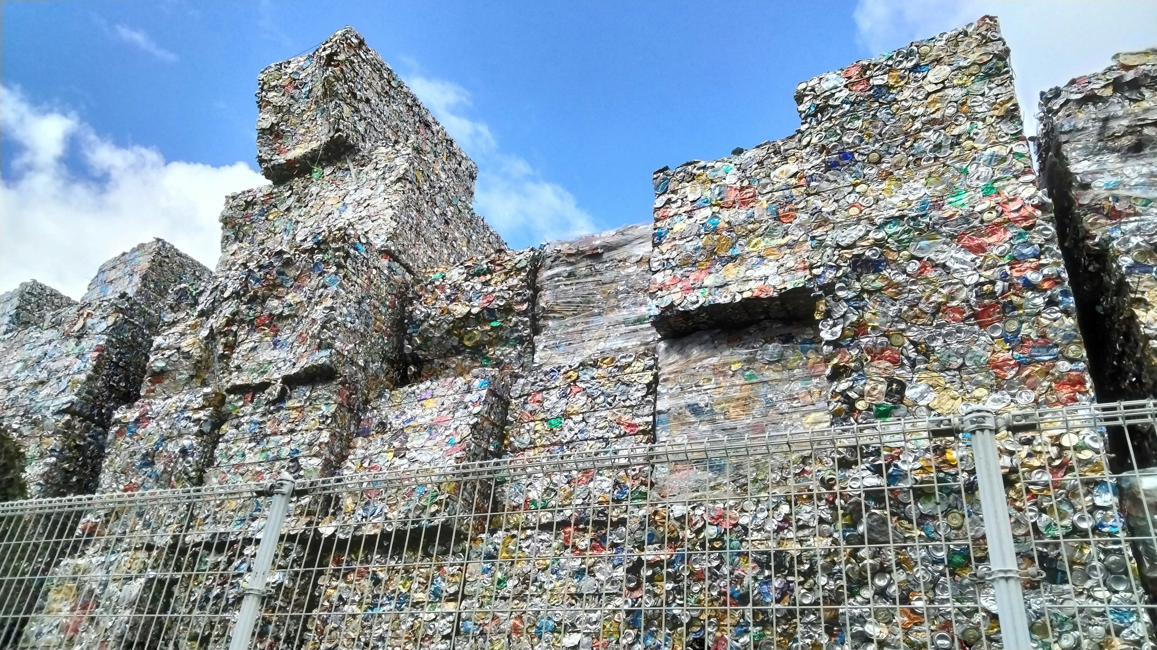 A landscape of stacked plastic waste under a blue sky