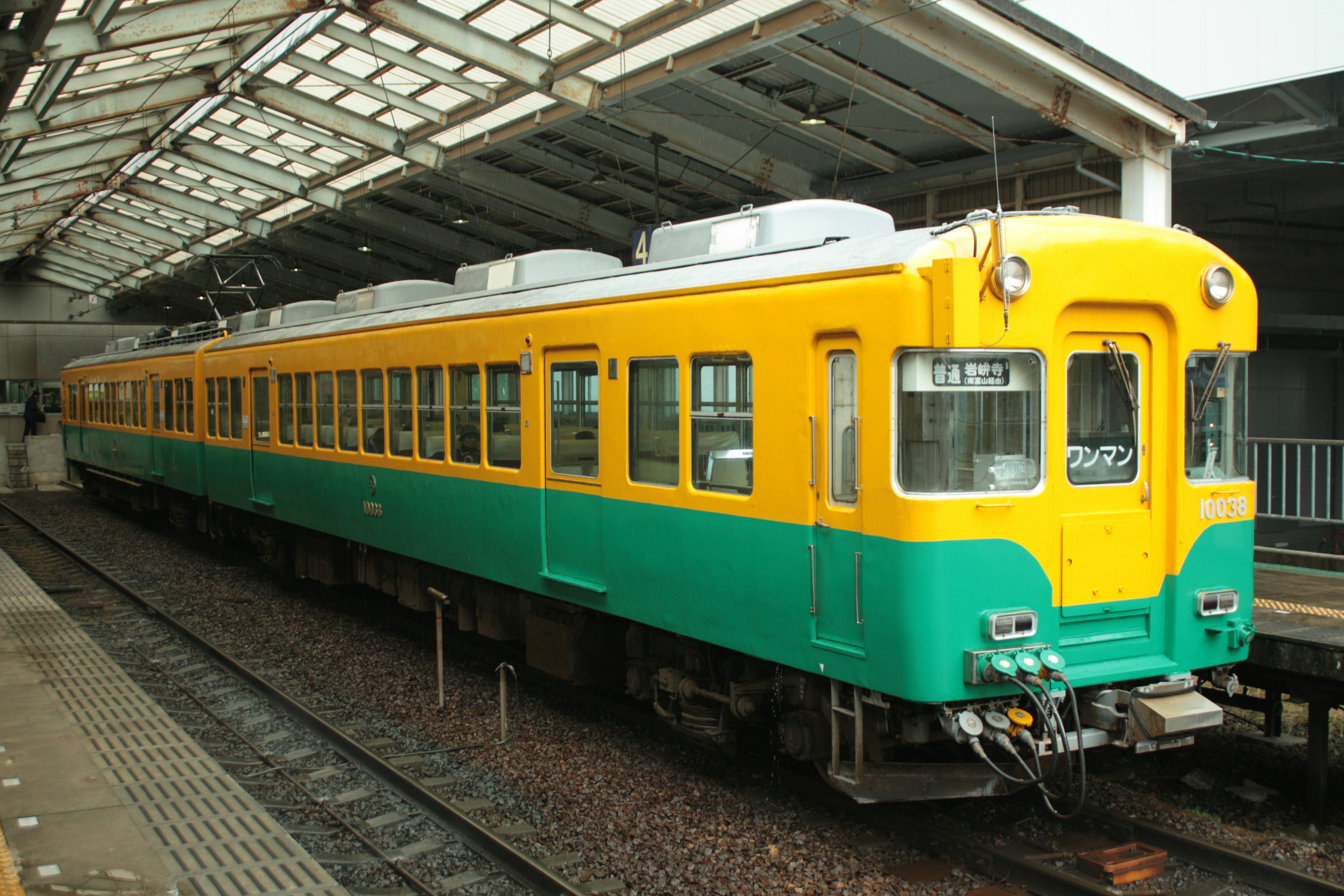 Sebuah kereta kuning dan hijau diparkir di stasiun