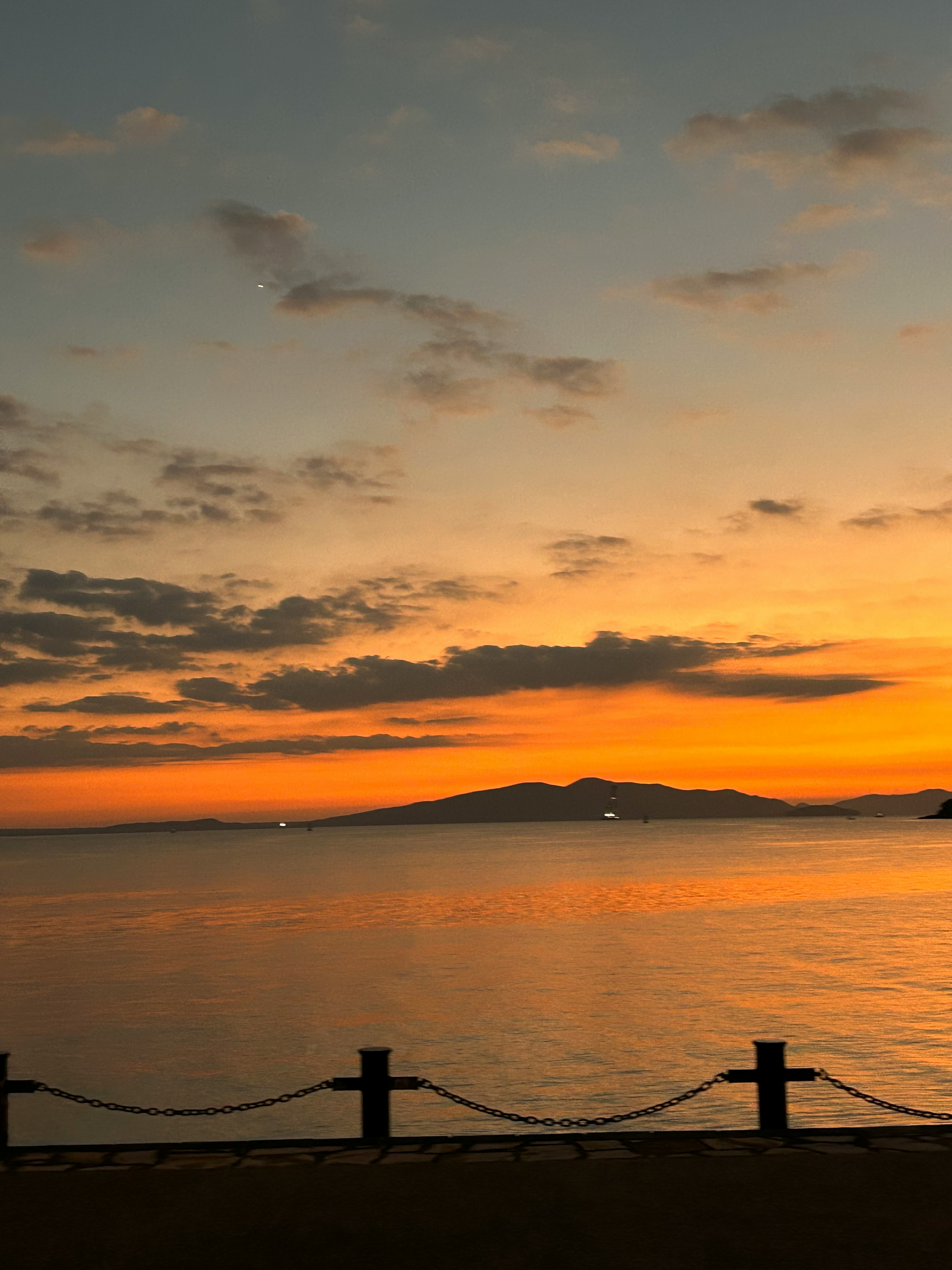 夕焼けの海岸の風景に浮かぶ島と穏やかな水面