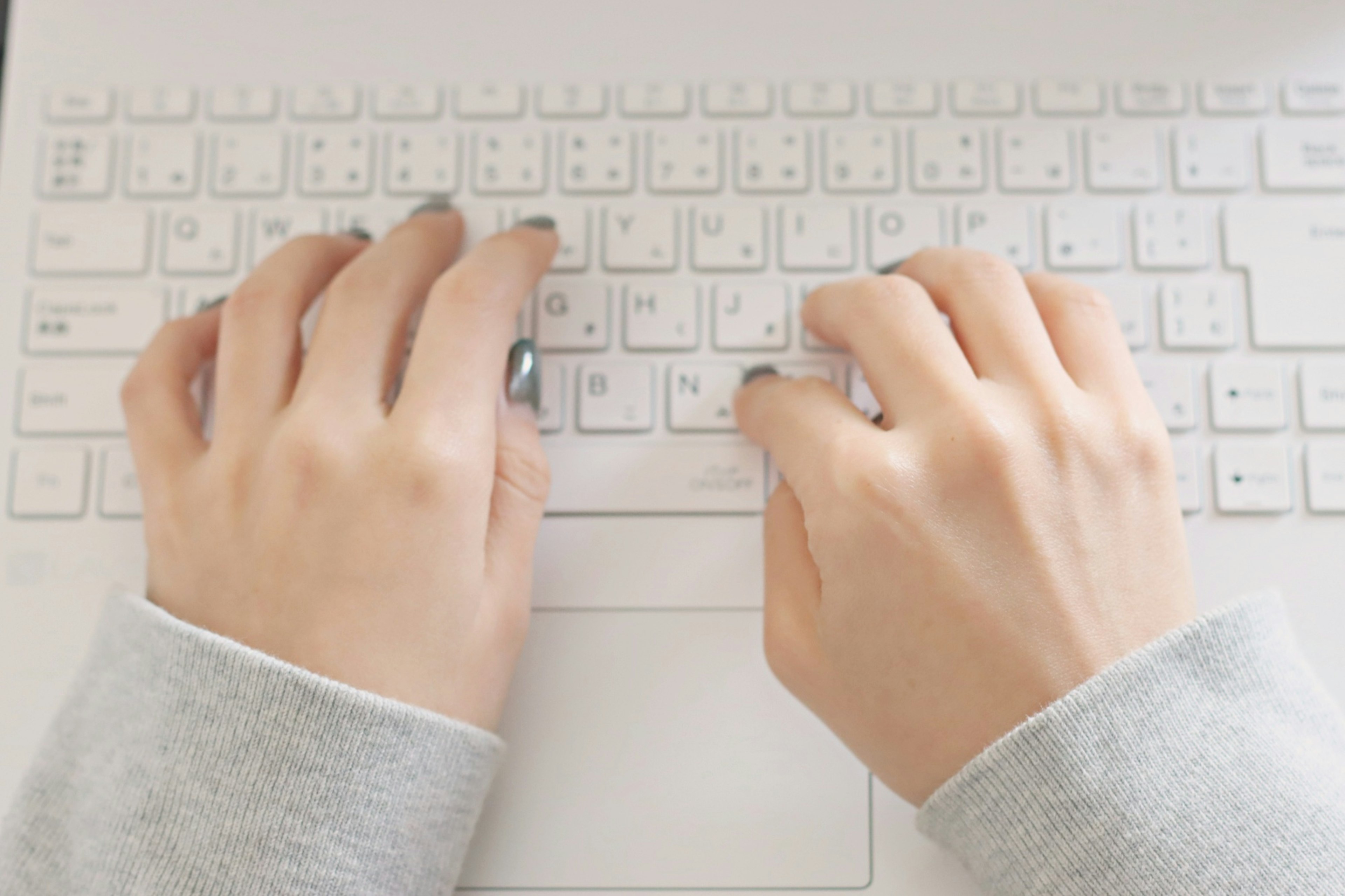 Hands typing on a white keyboard