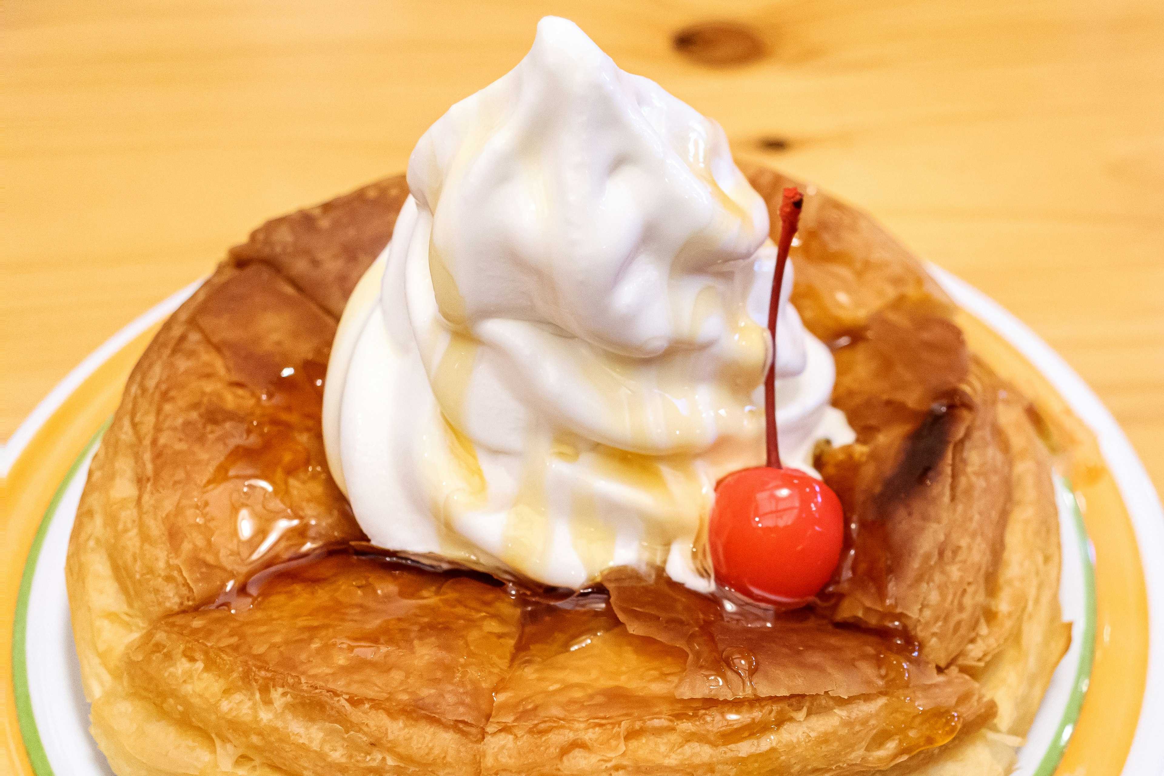 Fluffy pancake topped with soft serve ice cream and a cherry