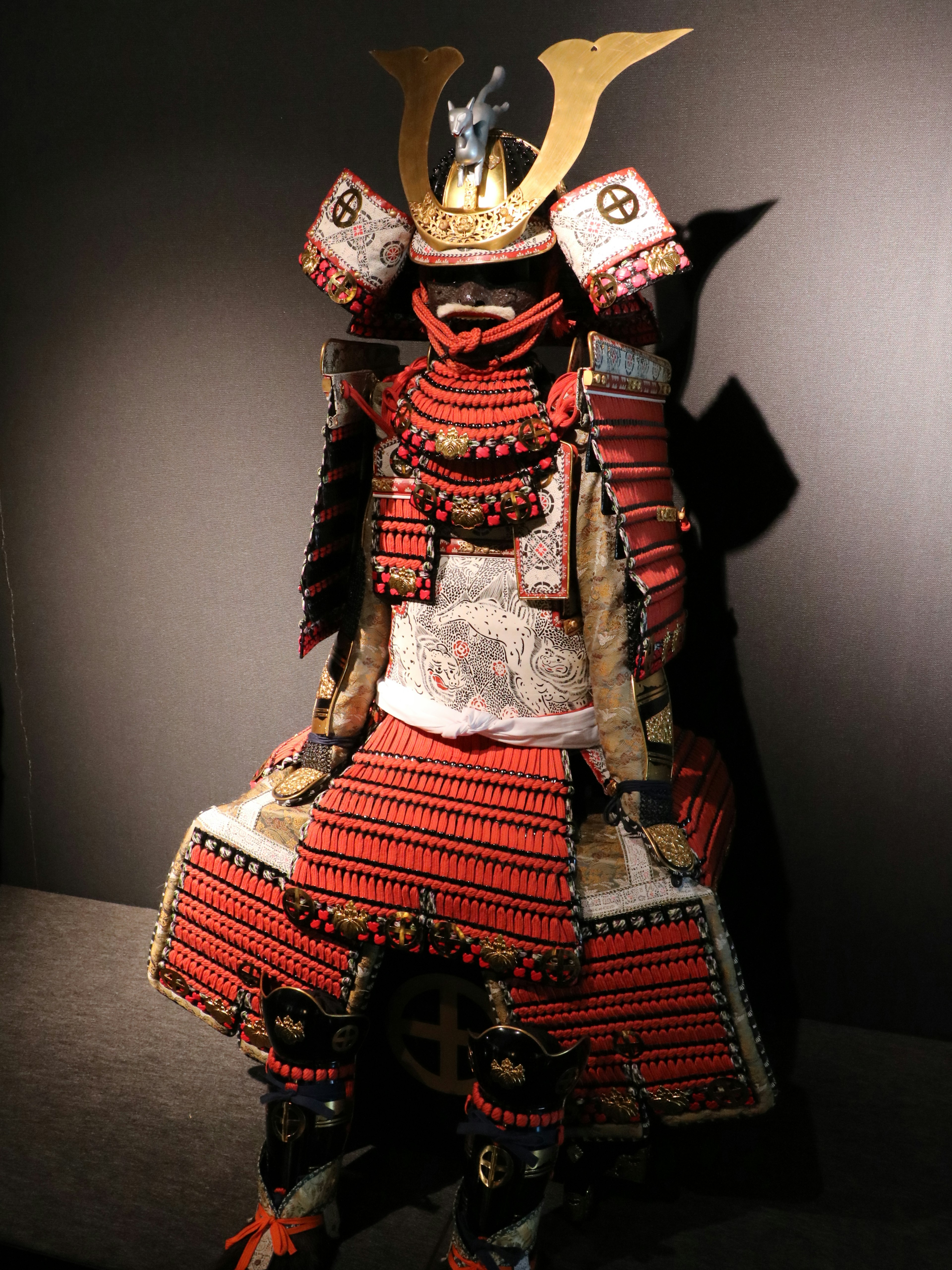 Una statua di samurai con un'armatura rossa esposta in un museo