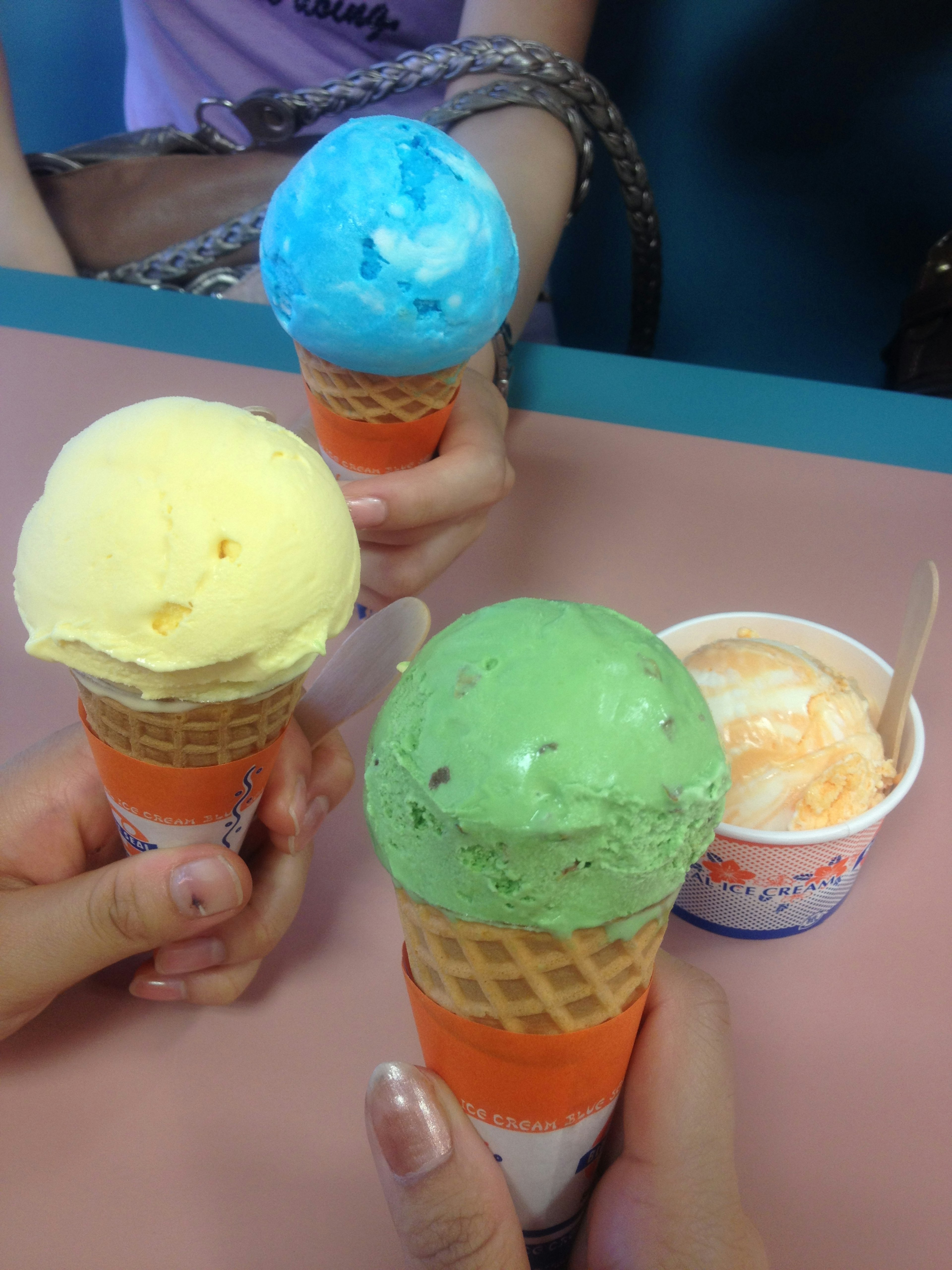 Conos de helado coloridos y taza sostenidos en manos