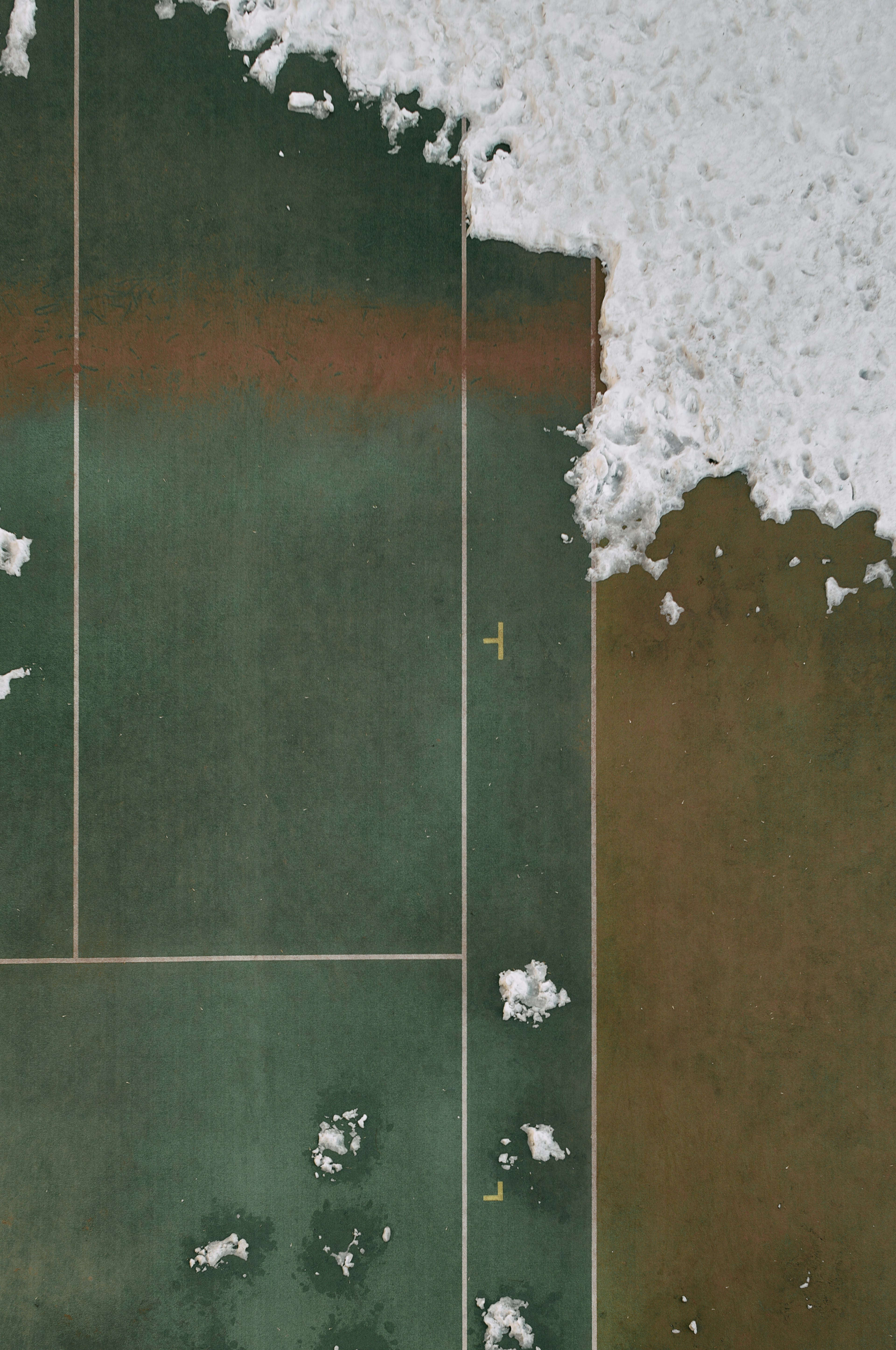 Vue aérienne d'un court de tennis vert avec de la mousse blanche provenant des vagues