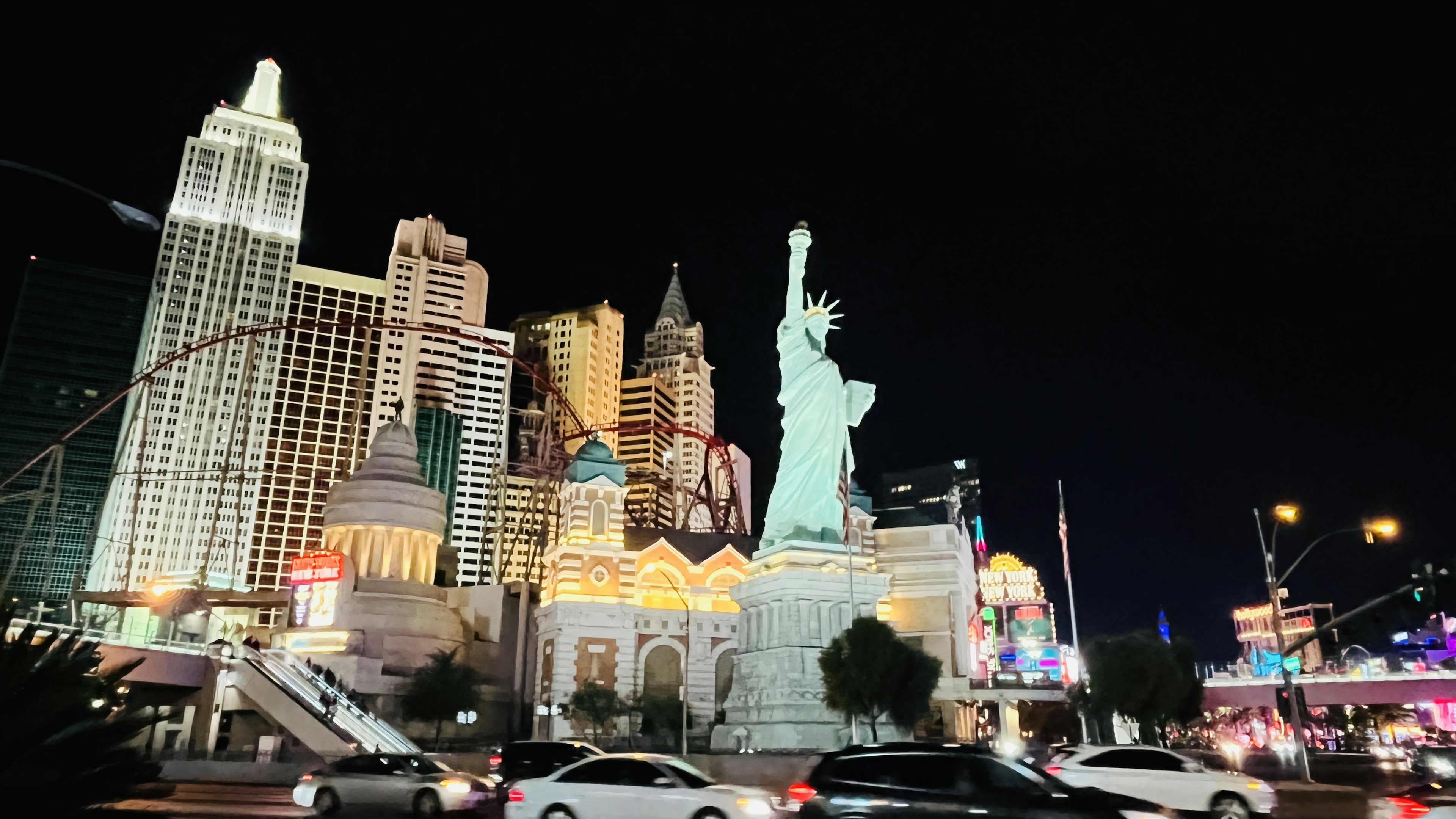 Tượng Nữ thần Tự do vào ban đêm với đường chân trời Las Vegas và các tòa nhà sòng bạc sáng đèn