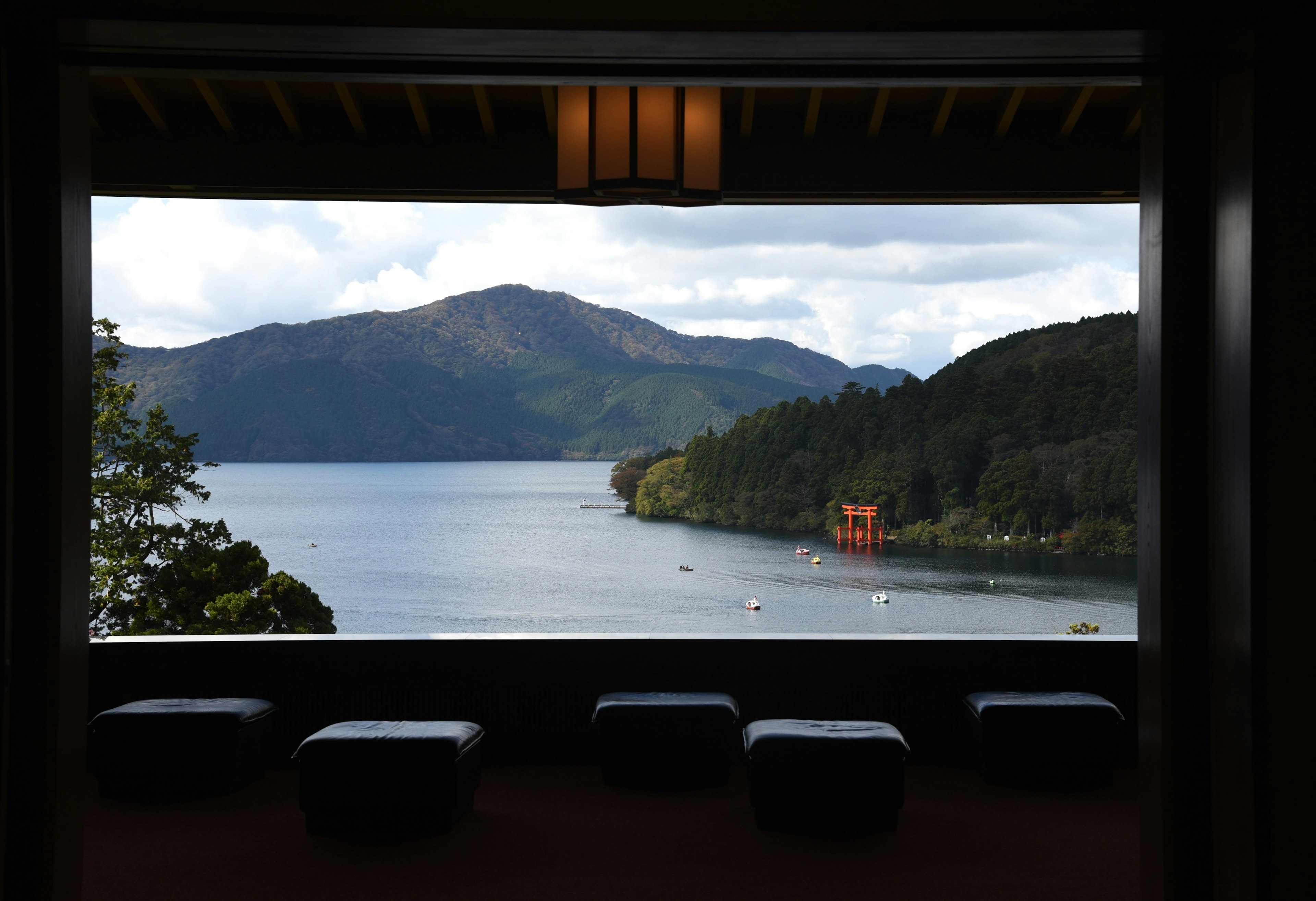 View of a lake and mountains with a red torii gate seen through a window