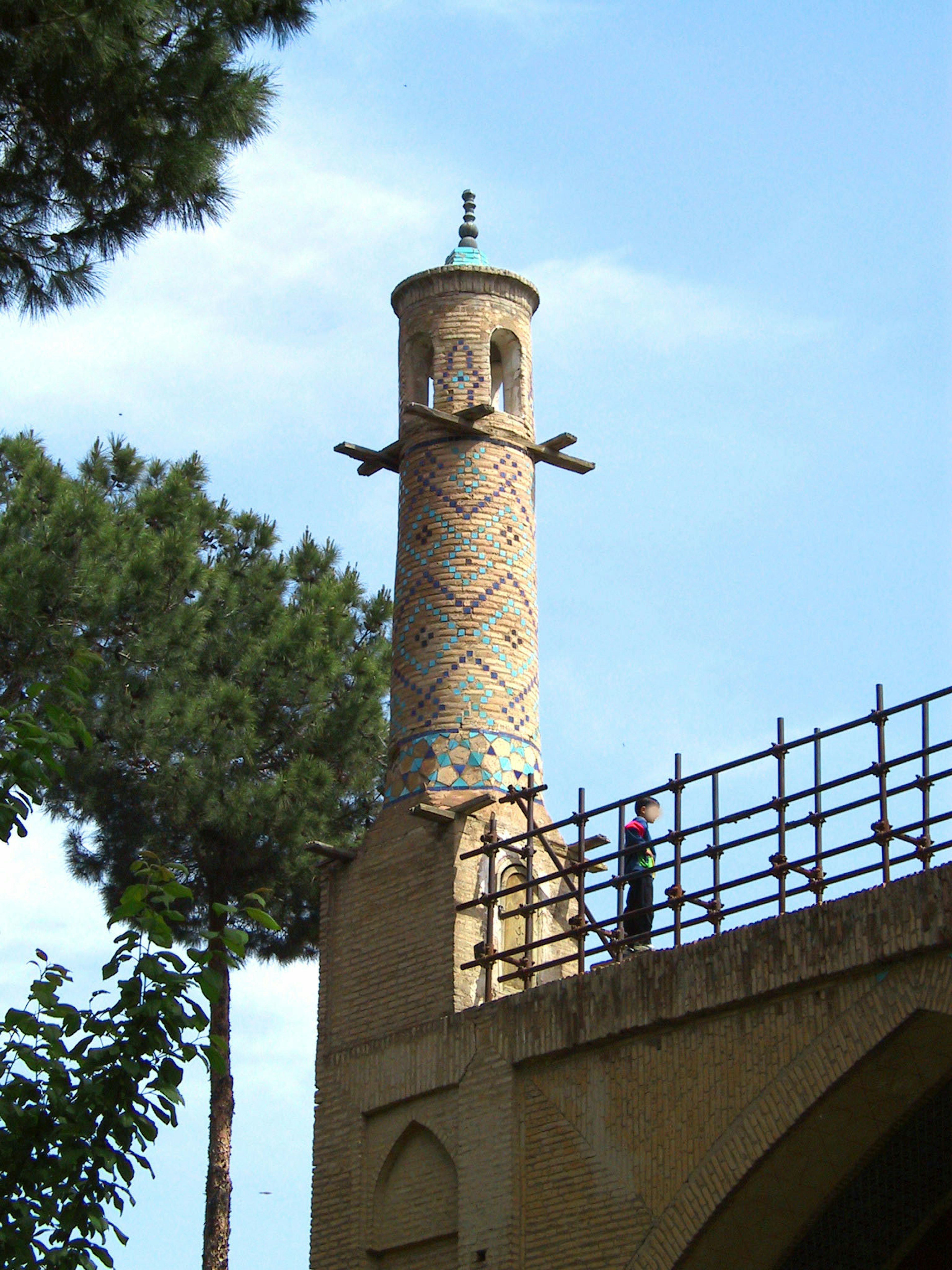 Decorative minaret stands beside a bridge