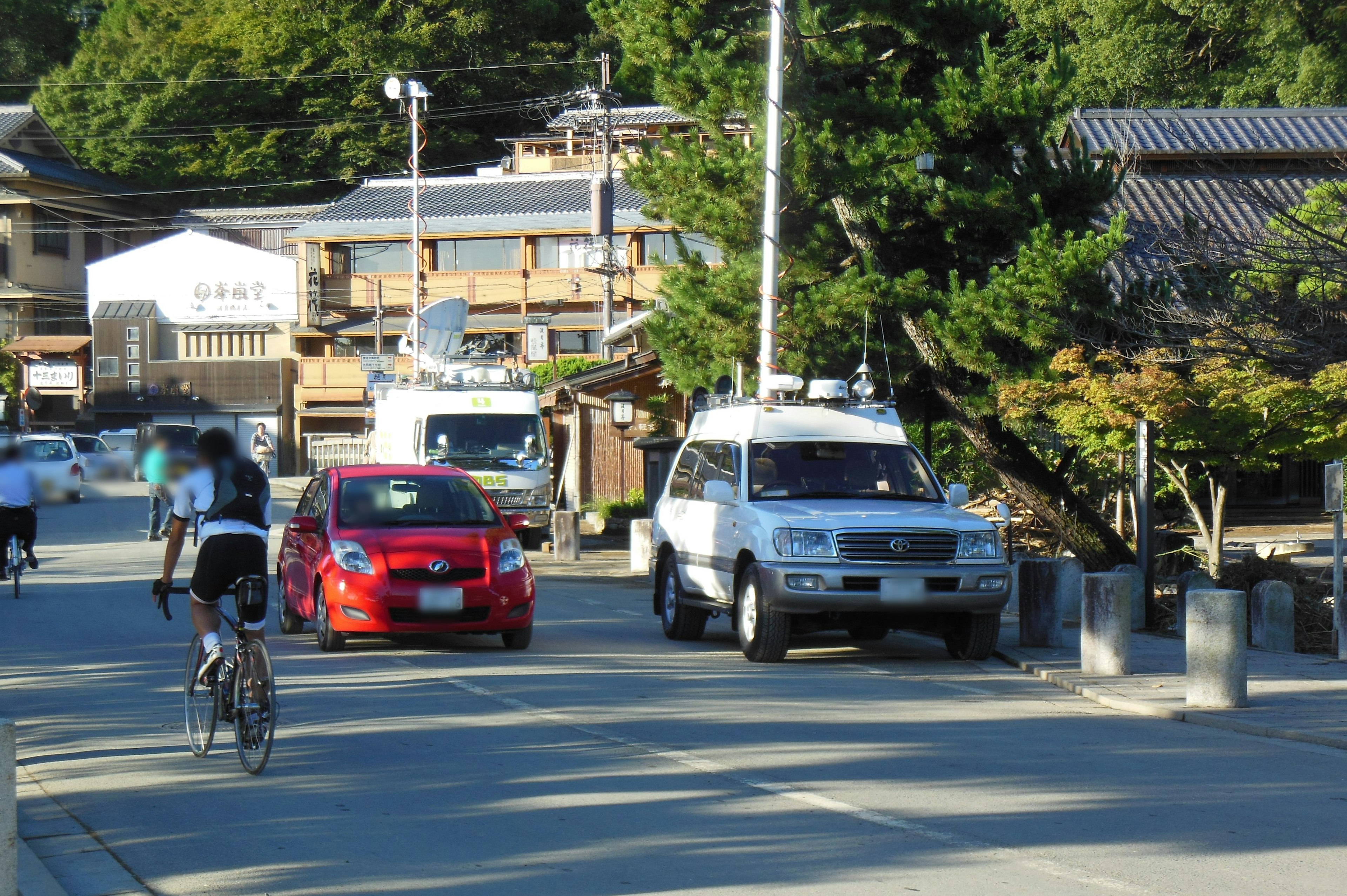 自転車に乗った人と車が走る静かな街の風景