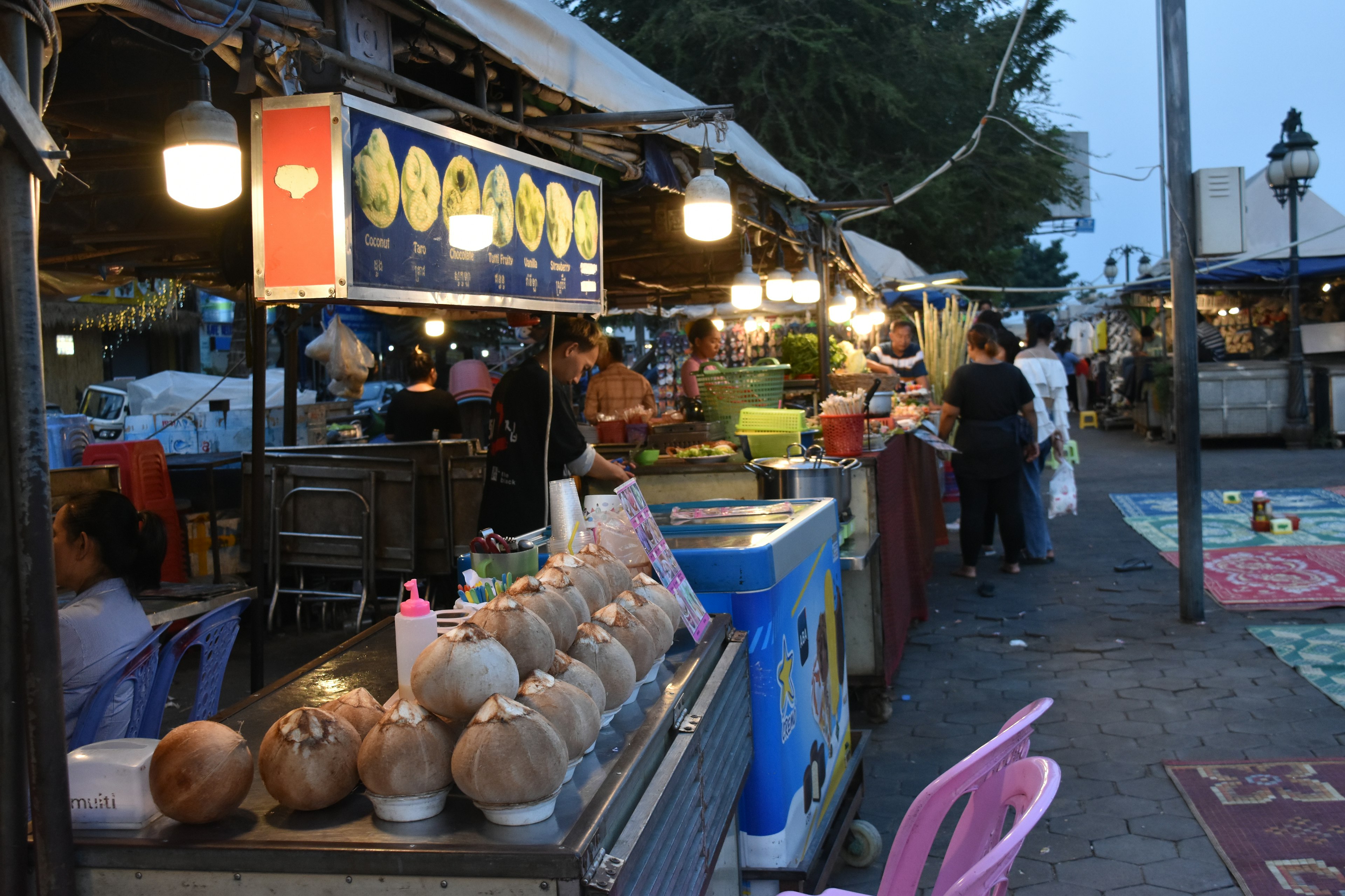 Scène de marché nocturne avec des stands de noix de coco et une activité animée